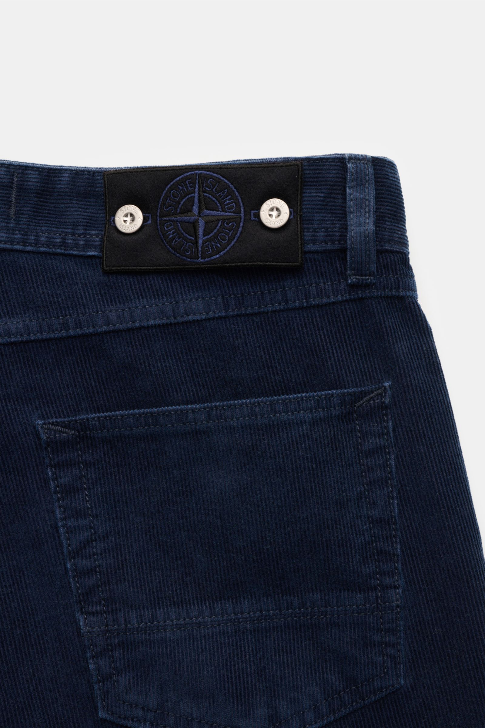 Close-up rear view of Stone Island Cordhose 'Micro Corduroy-Rinsed' navy, showing navy cotton-microfiber corduroy fabric, straight fit, five-pocket style, button fly, and signature compass badge on the waistband. Urbaner Klassiker in moderner Silhouette: 