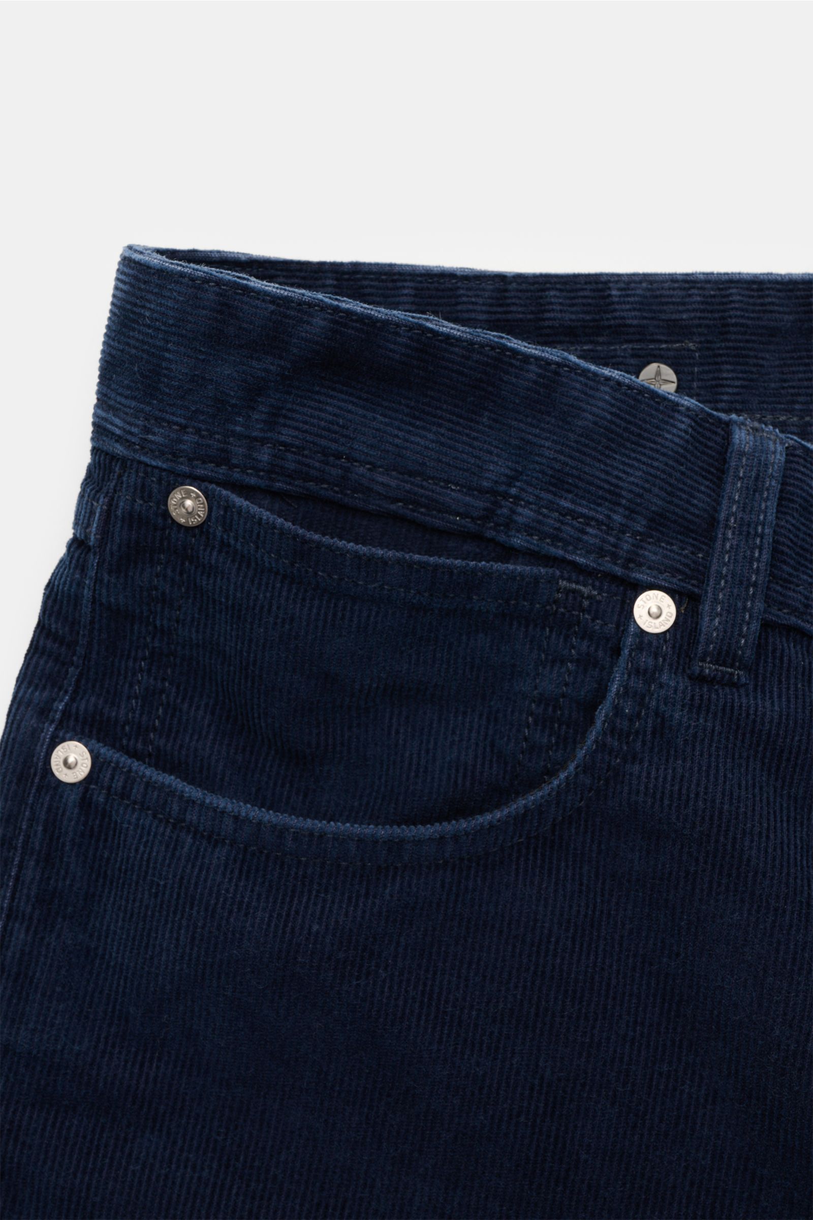 Close-up front view of Stone Island Cordhose 'Micro Corduroy-Rinsed' navy in straight fit cotton-microfiber blend with button fly, five-pocket style, and signature compass badge on waistband.