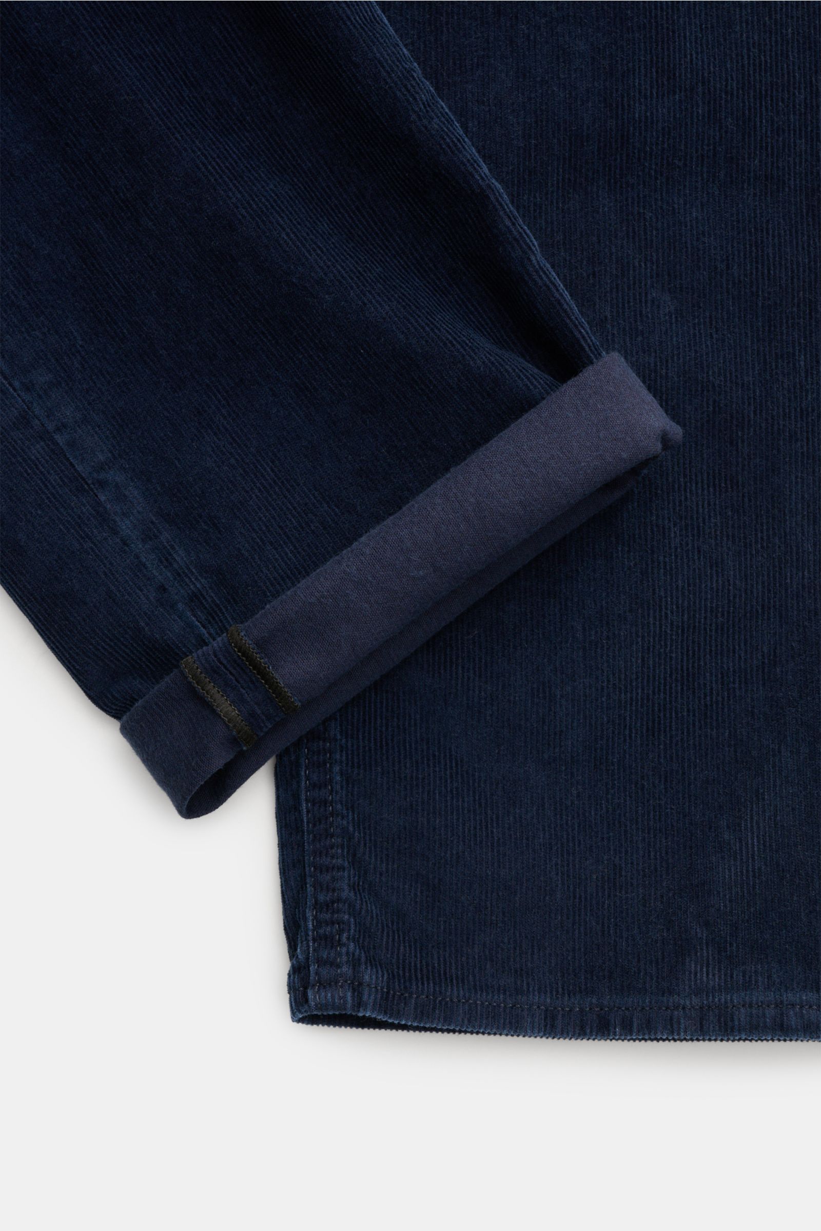Close-up of the cuff and lower leg of Stone Island Cordhose 'Micro Corduroy-Rinsed' navy, showing navy cotton-microfiber corduroy fabric with a rolled hem and visible stitching from a top-down perspective.