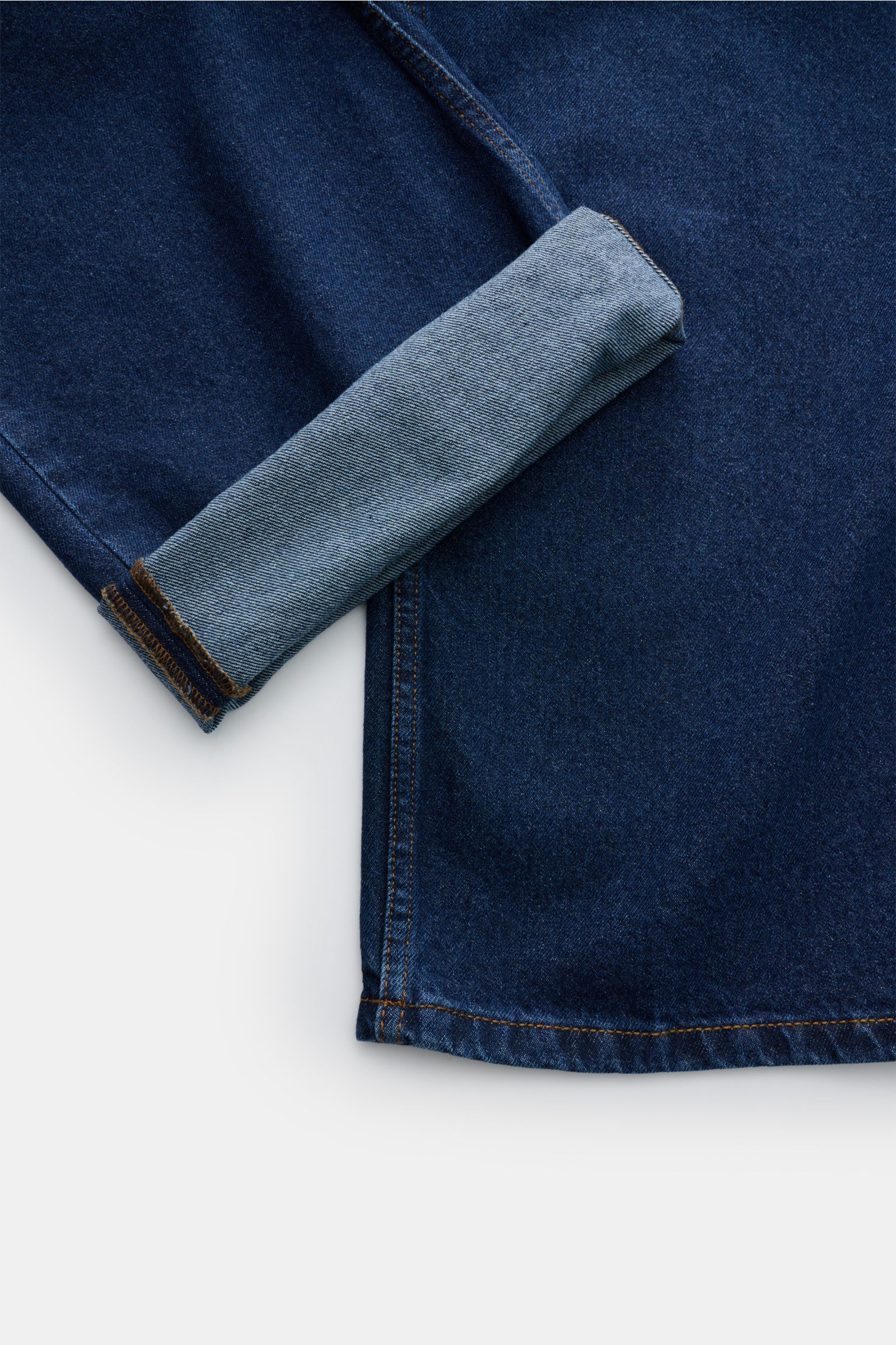 A close-up top-down view of the Ami Paris Jeans 'Large Fit' dunkelblau showing dark blue denim fabric with one cuff folded to reveal the lighter inner side. Moderner Loose Fit - AMI PARIS macht es vor: Mit dieser Jeans sind Sie garantiert gut angezogen, w