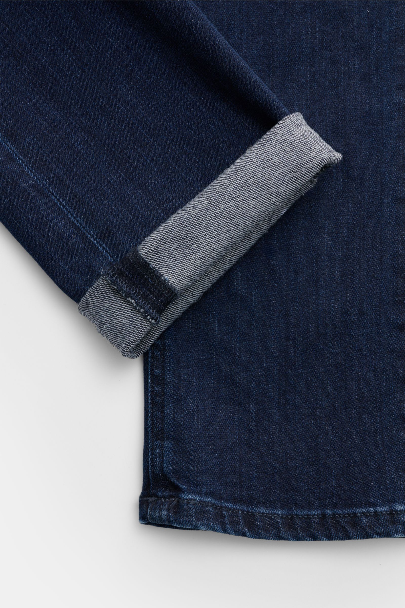 PT Torino Denim Jeans 'Jazz' dunkelblau, Slim Fit, aus leicht stretchigem Baumwoll-Mix mit weichem Griff, authentischer Used-Waschung, Button Fly, Five-Pocket-Stil und Veloursleder-Patch, Detailansicht Beinumschlag von oben.