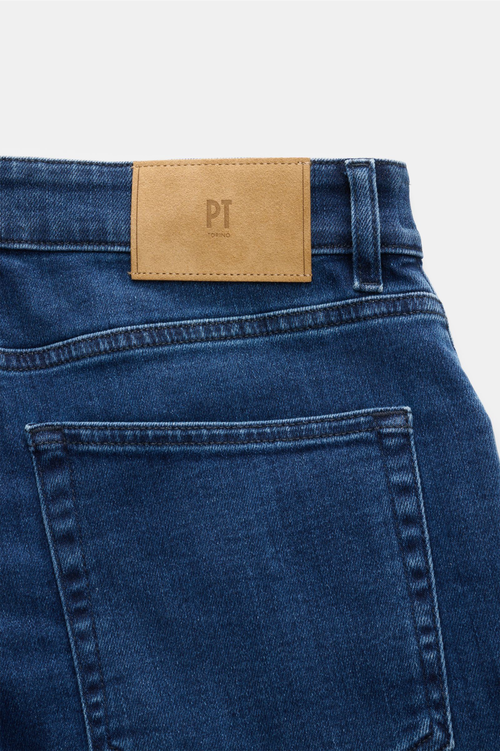 Close-up rear view of PT Torino Denim Jeans 'Jazz' dunkelblau showing dark blue denim fabric, a leather patch with 'PT Torino' logo, and classic five-pocket style. Für alle, die zeitlosen Stil mit maximalem Komfort verbinden wollen: Die Jeans 'Jazz' von P