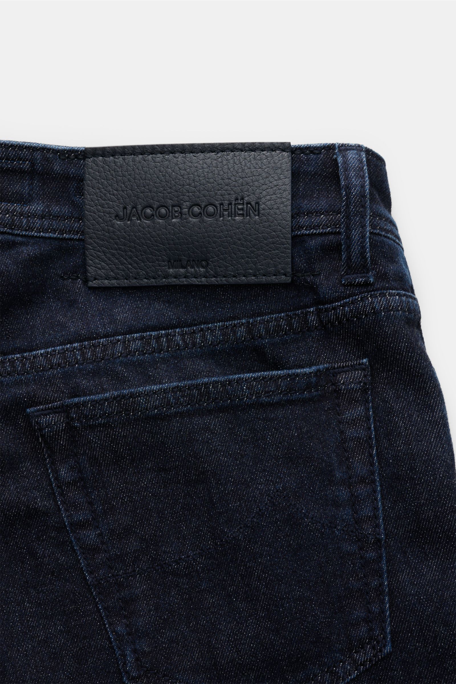 Close-up rear view of Jacob Cohen Jeans 'Bard' navy showing dark denim with cotton and cashmere, soft touch, slim fit, tapered, button fly, five-pocket style, coin pocket with initial, tonal stitching on back pockets, and leather patch.