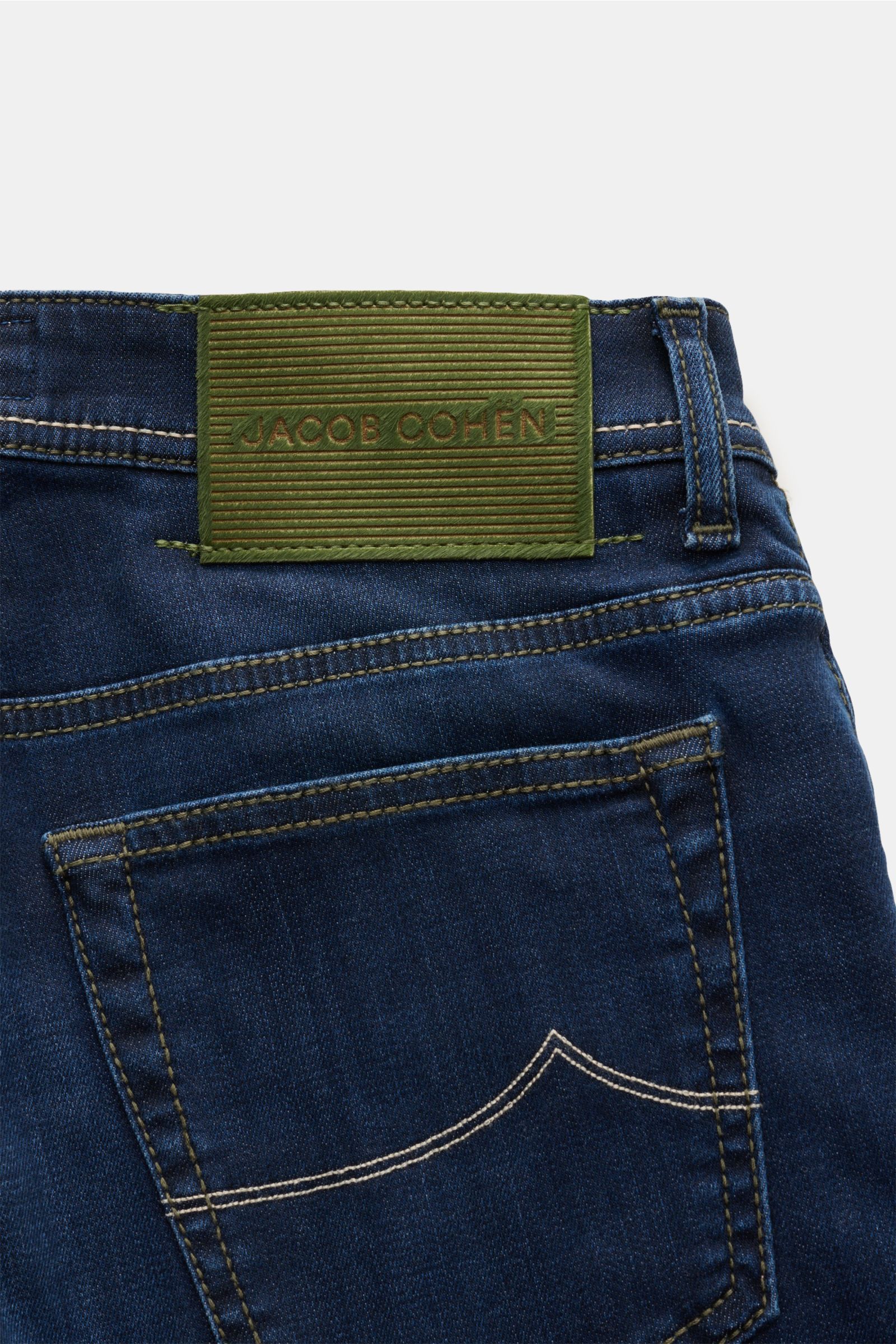 Close-up rear view of Jacob Cohen Jeans 'Bard' navy showing soft denim with contrast stitching, button fly, five-pocket style, coin pocket with initial, back pockets with stitching, and a pony hair-look leather patch. Denim made from cotton, lyocell, and 