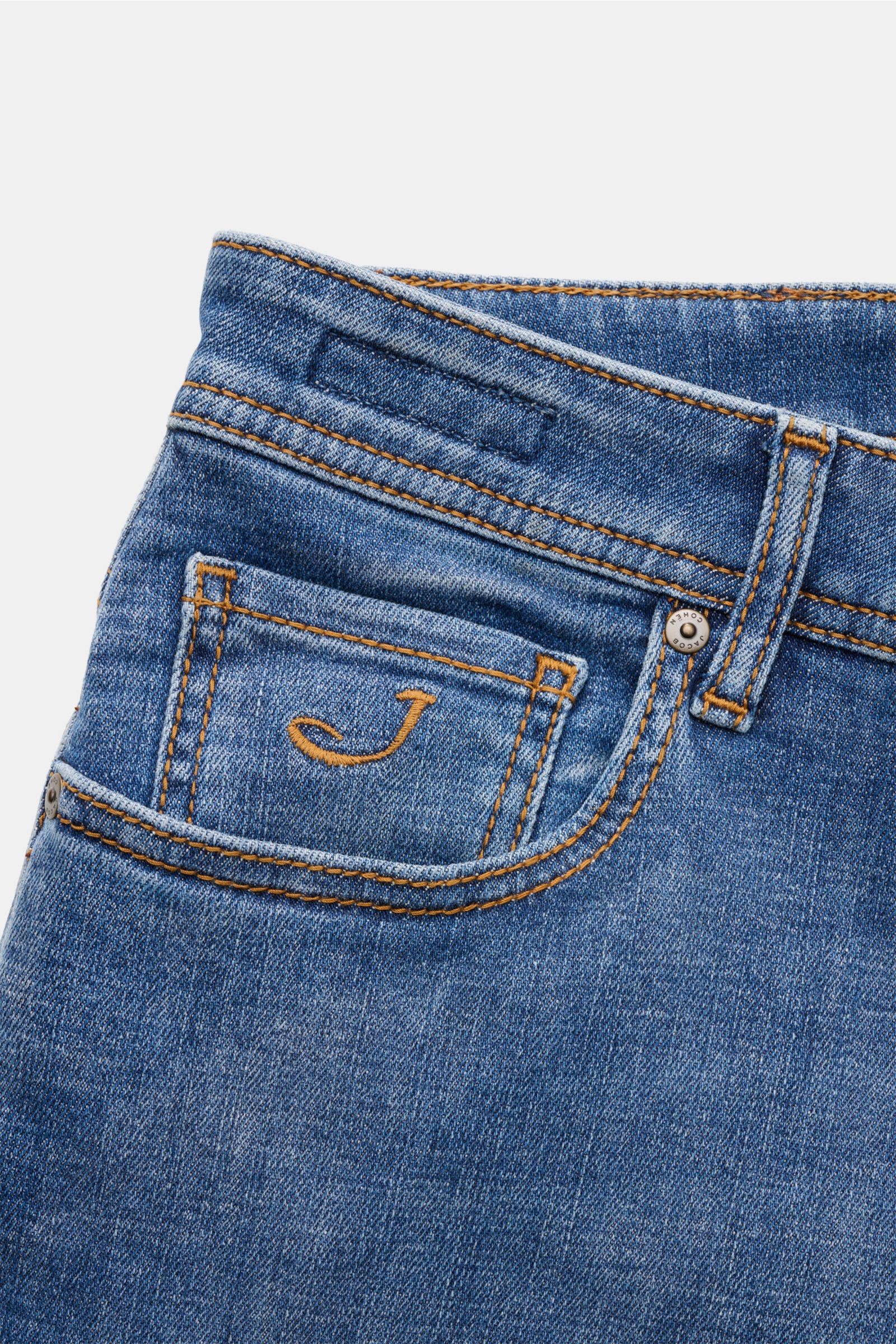 Close-up front-side view of Jacob Cohen Jeans 'Bard' blau showing denim aus Baumwolle, leicht elastische Qualität, weicher Griff, leichte Used-Waschung, Slim Fit, schmal zulaufend, Button Fly, Five-Pocket-Stil, Münztasche mit Initial, Kalbfell-Patch.