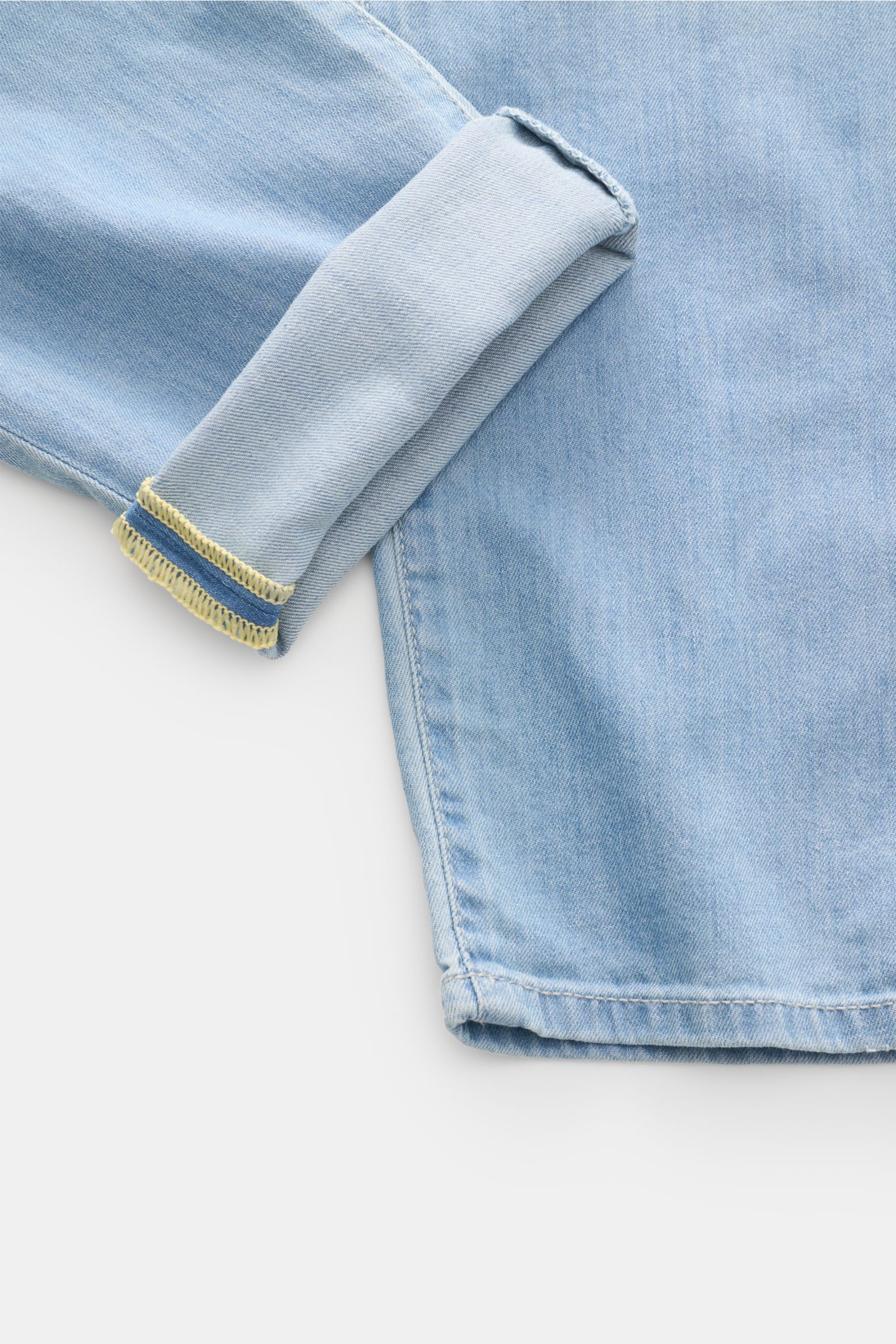 Close-up side view of Ace Denim Jeans 'AD 15 bleached' light blue showing folded cuff with yellow stitching, highlighting cotton, lyocell, linen blend, slight stretch, soft feel, authentic used wash, slim fit, very tapered cut, button fly, five-pocket sty