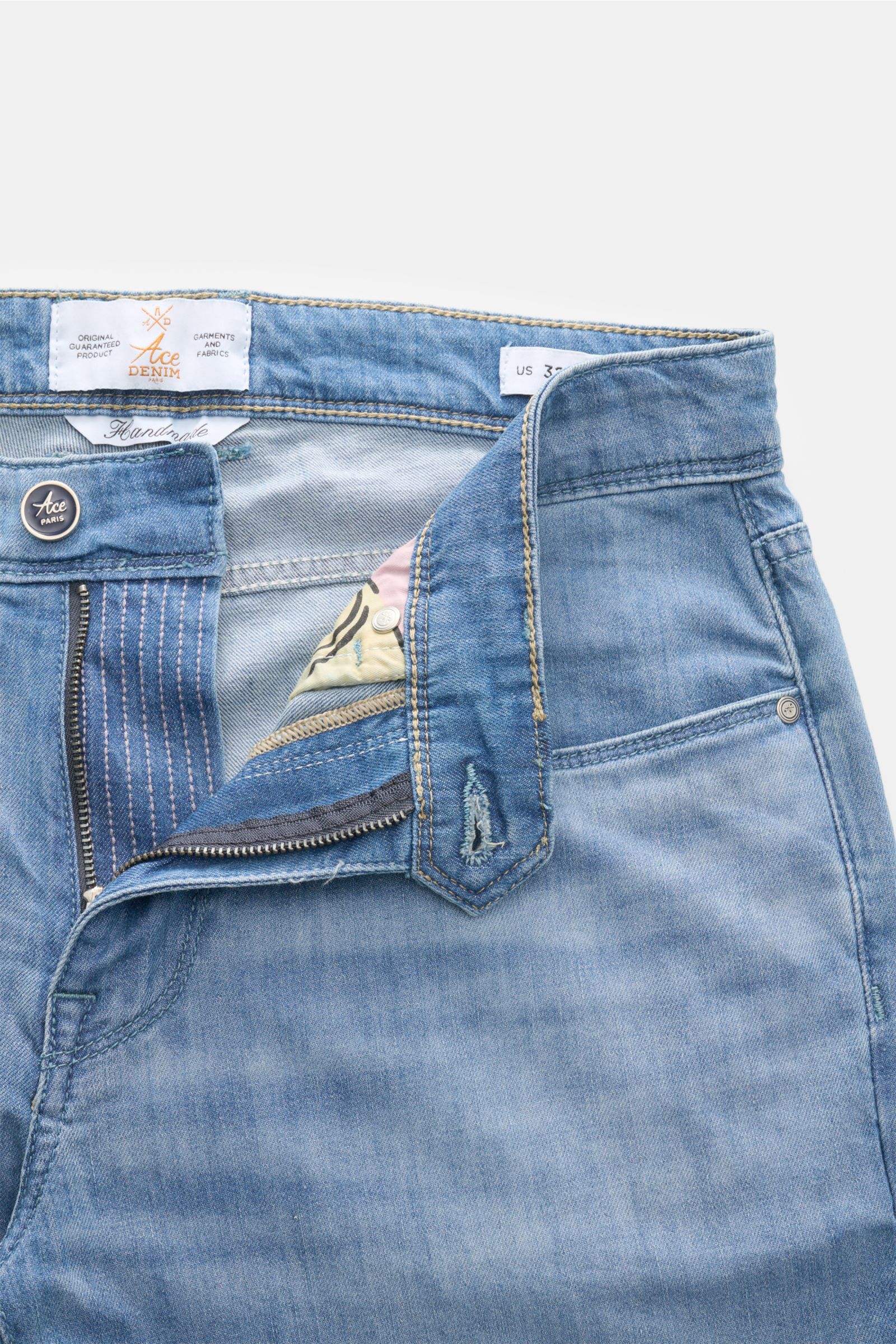 Close-up, top-front angled view of Ace Denim Jeans 'AD 15 bleached' smoky blue showing button fly, zipper, and fabric texture with soft, authentic used wash. ACE DENIM stands for hand-made jeans and sustainable production processes – the model 'AD 15' is 