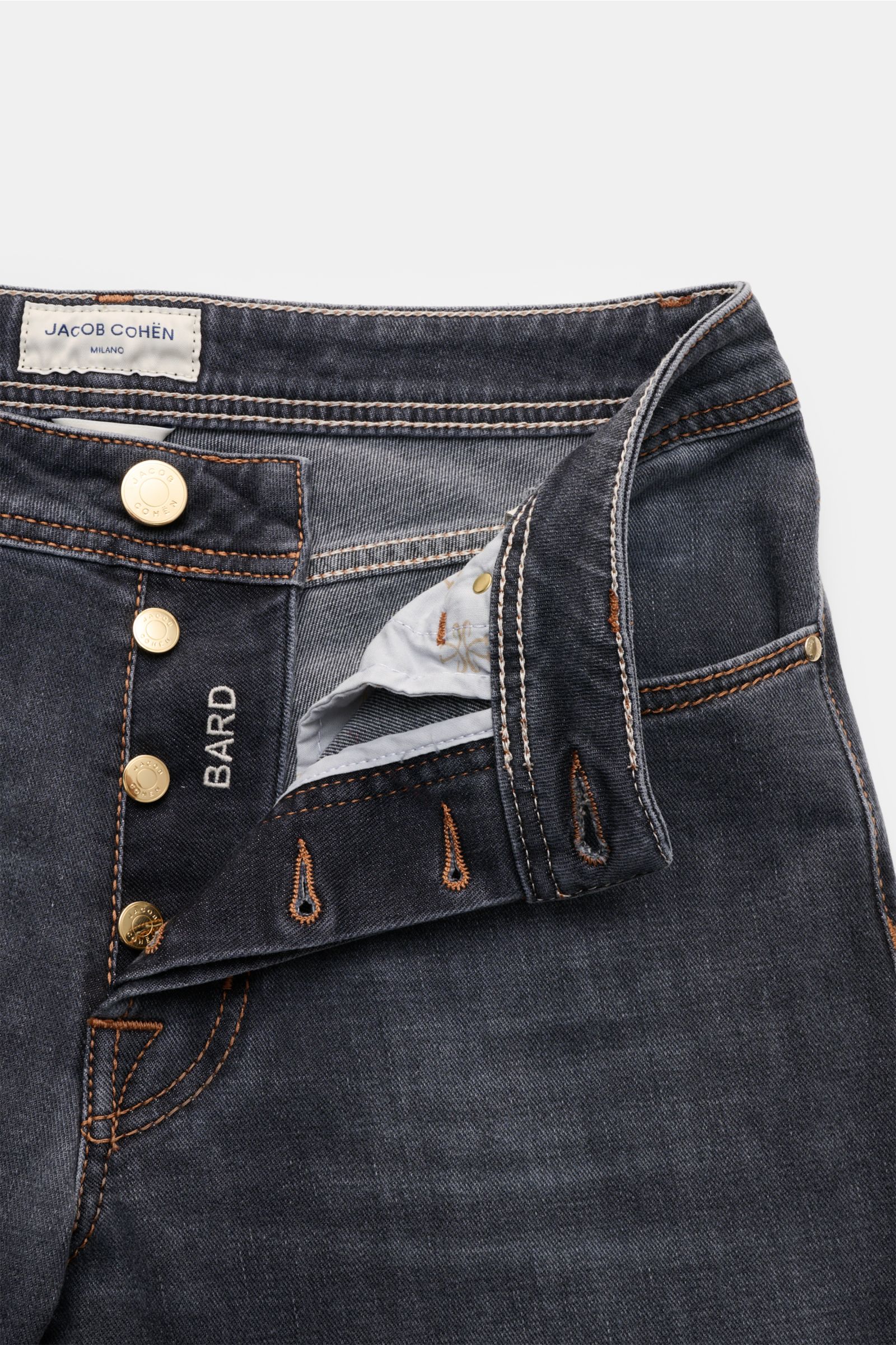 Close-up front view of Jacob Cohen Jeans 'Bard' grau with button fly, grey denim, orange stitching, and visible brand label.

Mit dem luxuriösen Slim Fit Klassiker 'Bard' von JACOB COHEN liegen Sie immer richtig: Die leicht elastische Mischung aus Baum