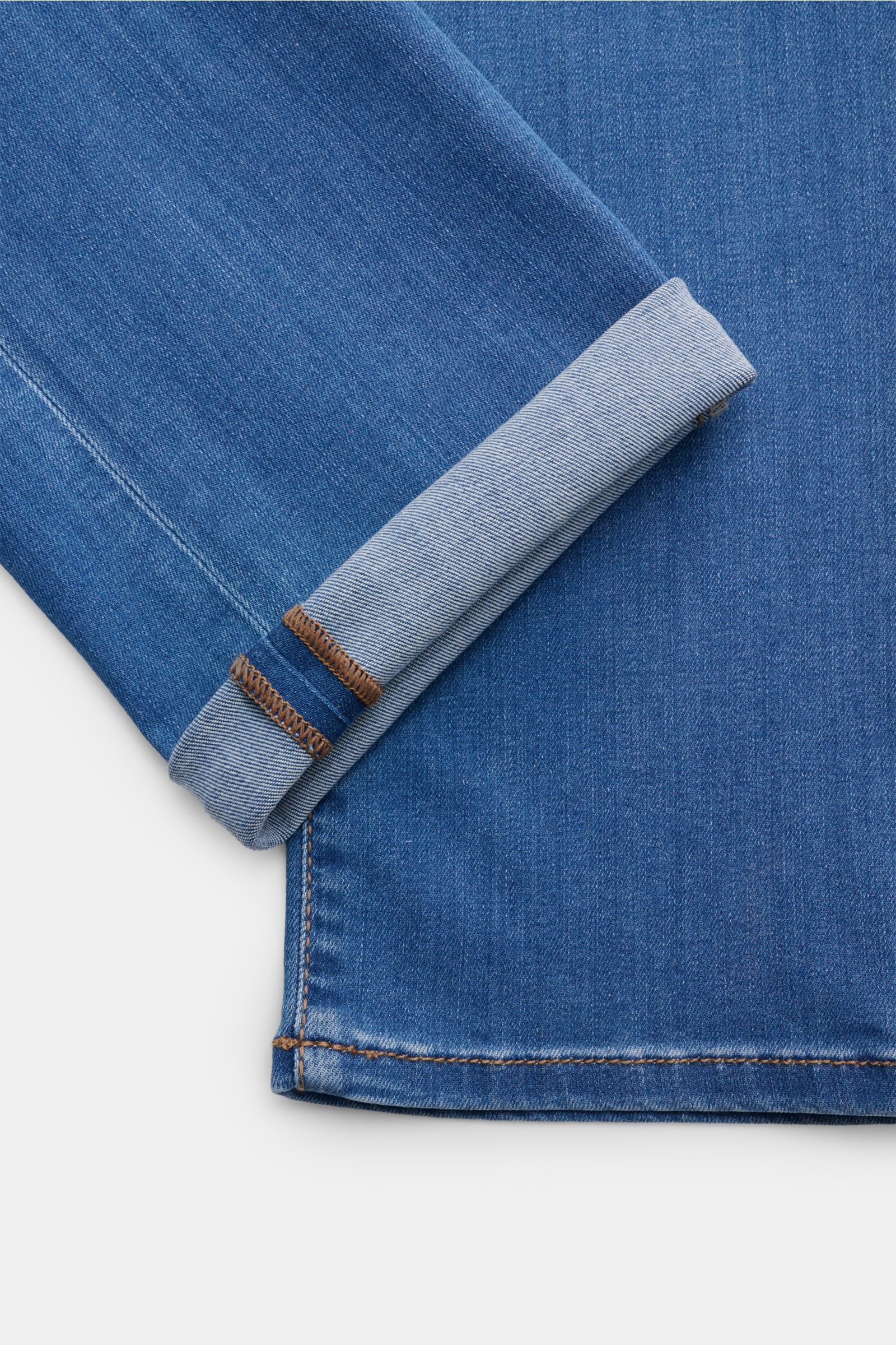 Jacob Cohen Jeans 'Bard' blau shown from a close-up top-down view, highlighting soft, slim-fit denim with rolled cuff and fine stitching. Modern luxury for everyday wear: the premium jeans blend viscose, cotton, and lyocell for comfort and style.
