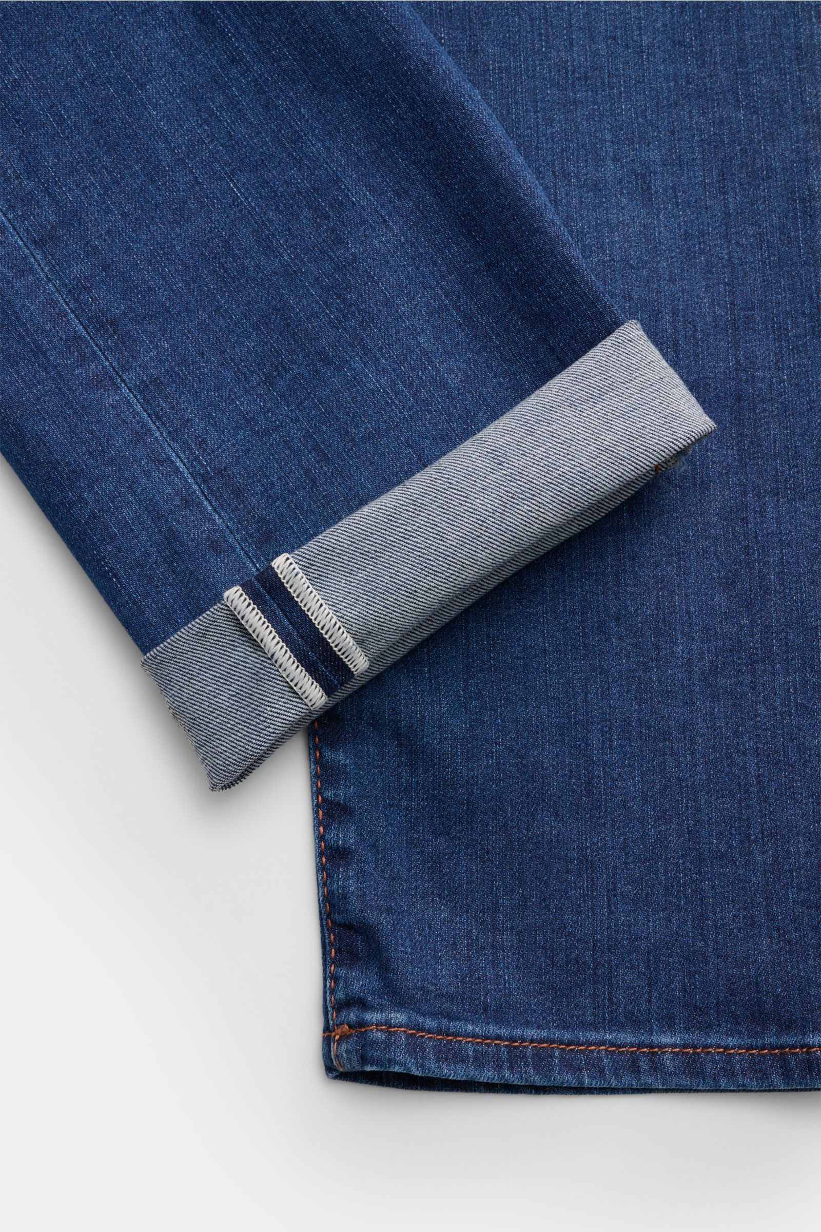 Close-up image of the cuff and hem of Jacob Cohen Jeans 'Bard' blau, photographed from above, showing elastic cotton denim with soft texture, slim fit, slight taper, button fly, five-pocket style, coin pocket with initial, back pockets with stitching, and