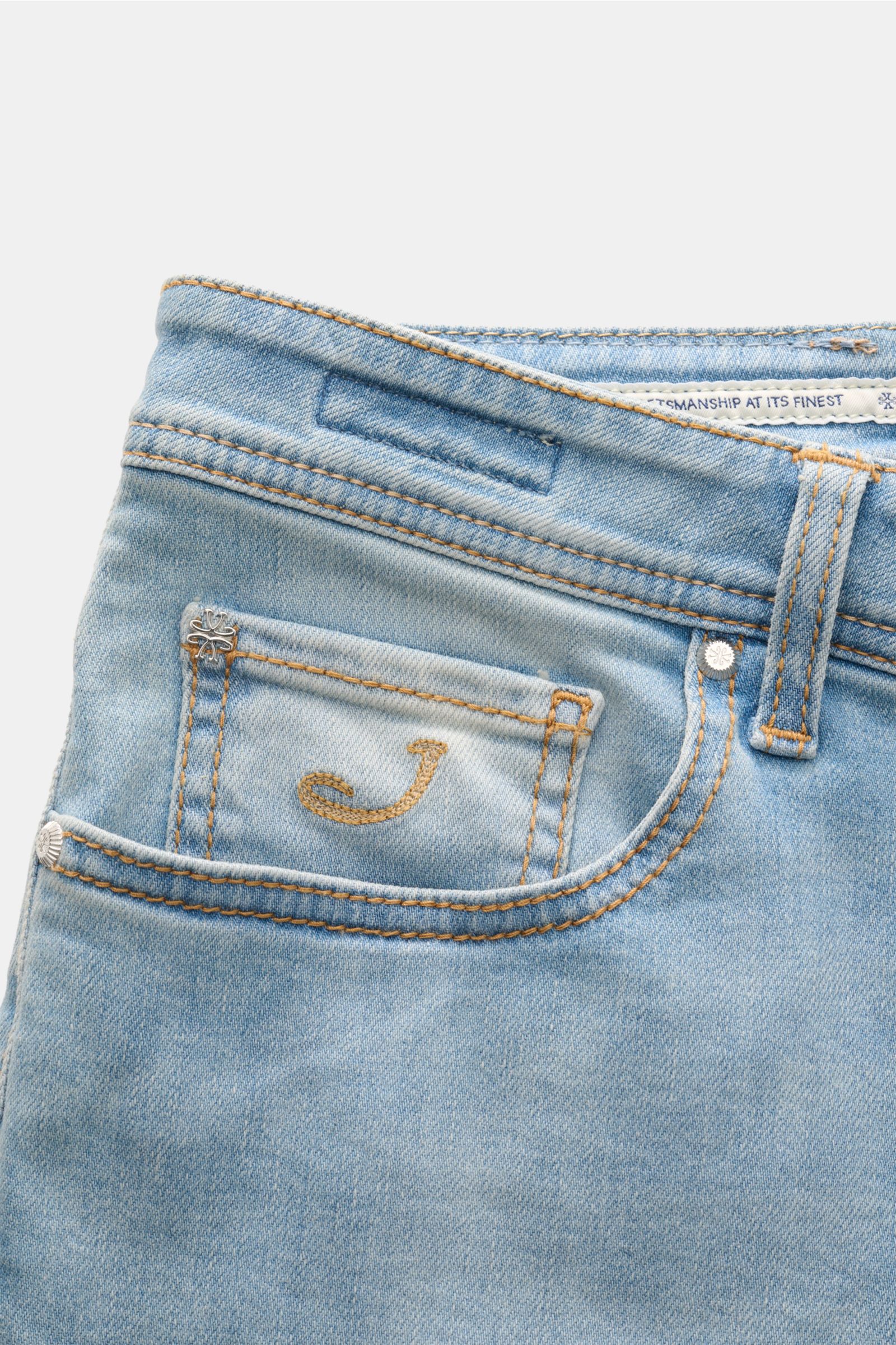 Close-up image of the front pocket area of Jacob Cohen Jeans 'Bard LTD' rauchblau, showing light blue denim with orange stitching, a small pocket with a gold embroidered 'J,' and silver rivets. Moderne Lässigkeit kombiniert mit unverwechselbaren Details: 