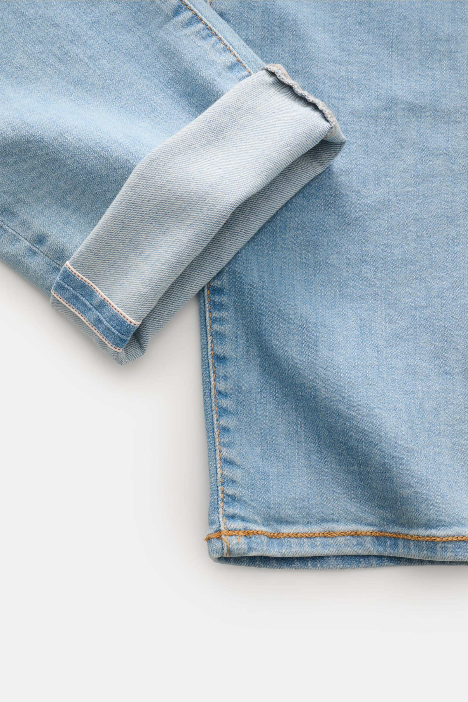 Close-up of the cuff and hem of Jacob Cohen Jeans 'Bard LTD' rauchblau, photographed from above, showing light blue denim fabric with selvedge stitching. Moderne Lässigkeit kombiniert mit unverwechselbaren Details: das auffällige Kalbfell-Patch ist das Ma