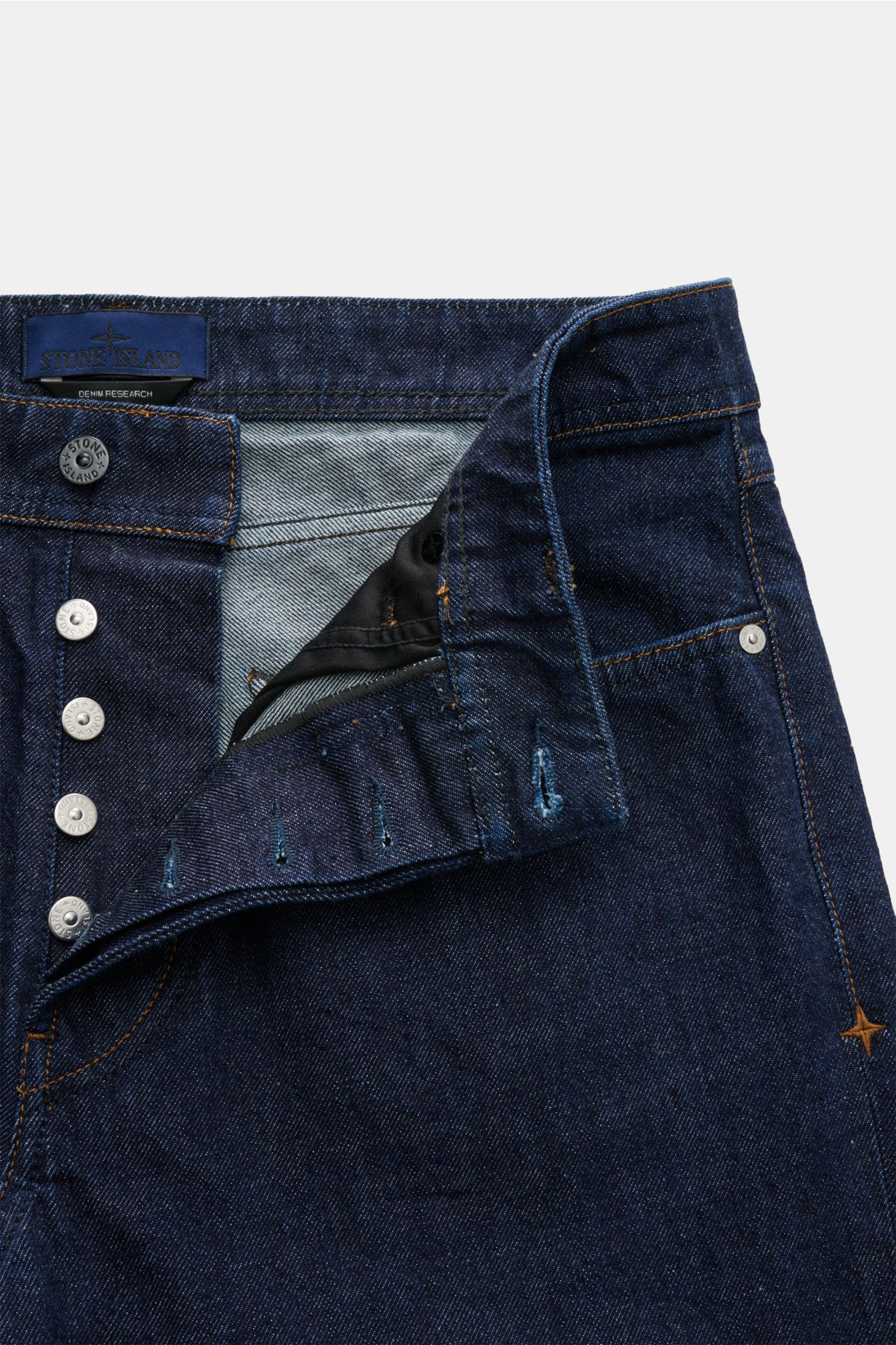 Close-up front view of Stone Island Jeans 'Indigo Denim - Rinsed' dunkelblau showing button fly, straight fit, five-pocket style, and compass badge on waistband.