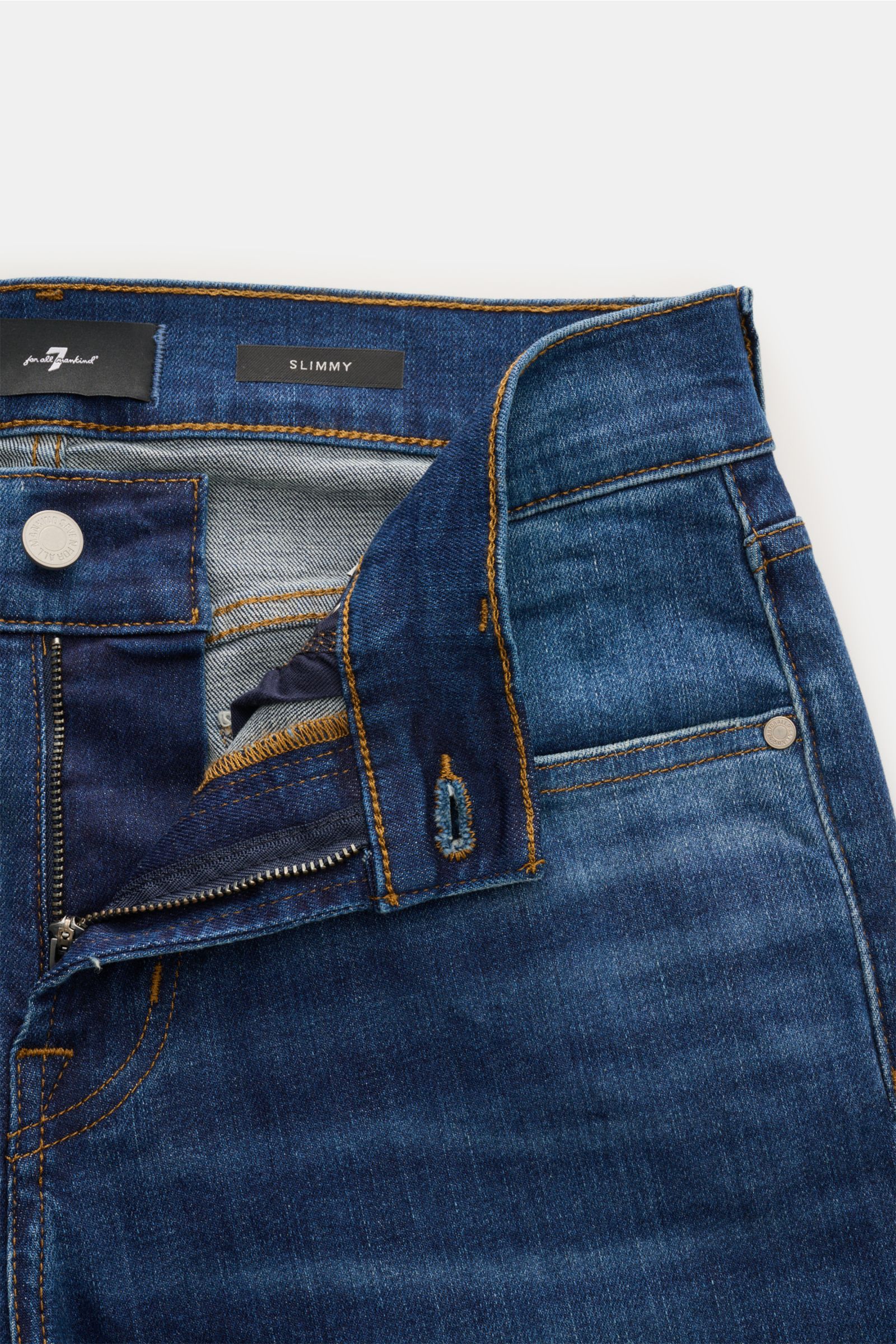Close-up front view of 7 for all mankind Jeans 'Slimmy' dark blue with zip fly, five-pocket style, authentic used wash, and small woven label on waistband. Seven pairs of jeans should be enough to get you through life – that’s the philosophy of denim labe