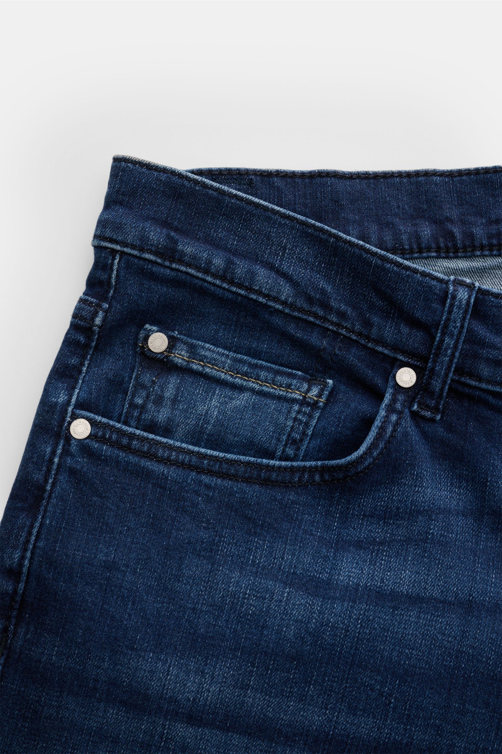 Close-up image of the front upper section of 7 for all mankind Jeans 'Slimmy' dark blue, photographed from above, showing elasticated cotton fabric with a subtle used wash, slim fit, slightly tapered cut, zip fly, five-pocket style including a small coin 