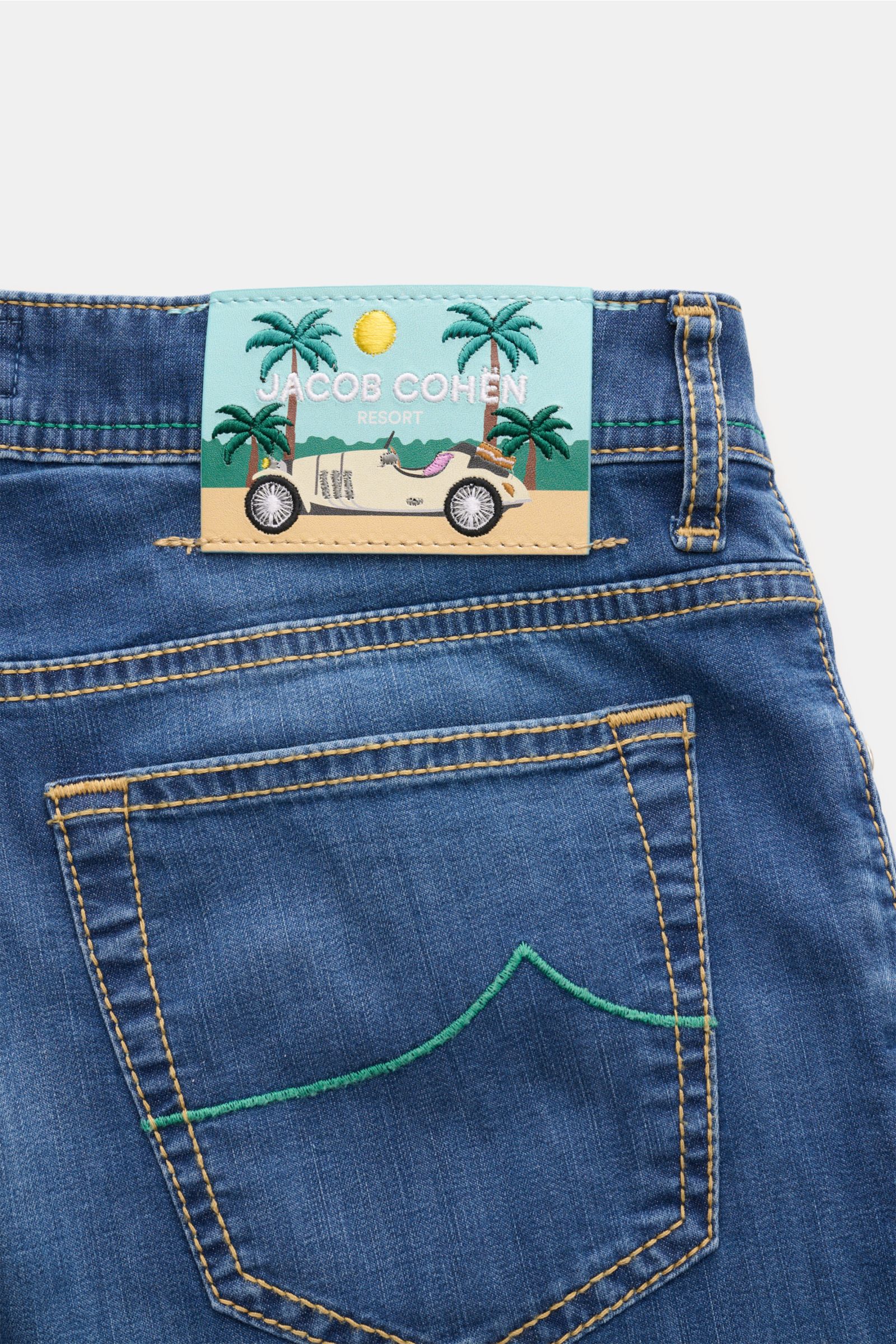 Jacob Cohen Jeans 'Bard' blau shown from the rear upper section, highlighting the back pocket with green stitching and a leather patch with car and palm trees. Premium-Denim from the Italian expert Jacob Cohen: The classic 'Bard' made of cotton with visco