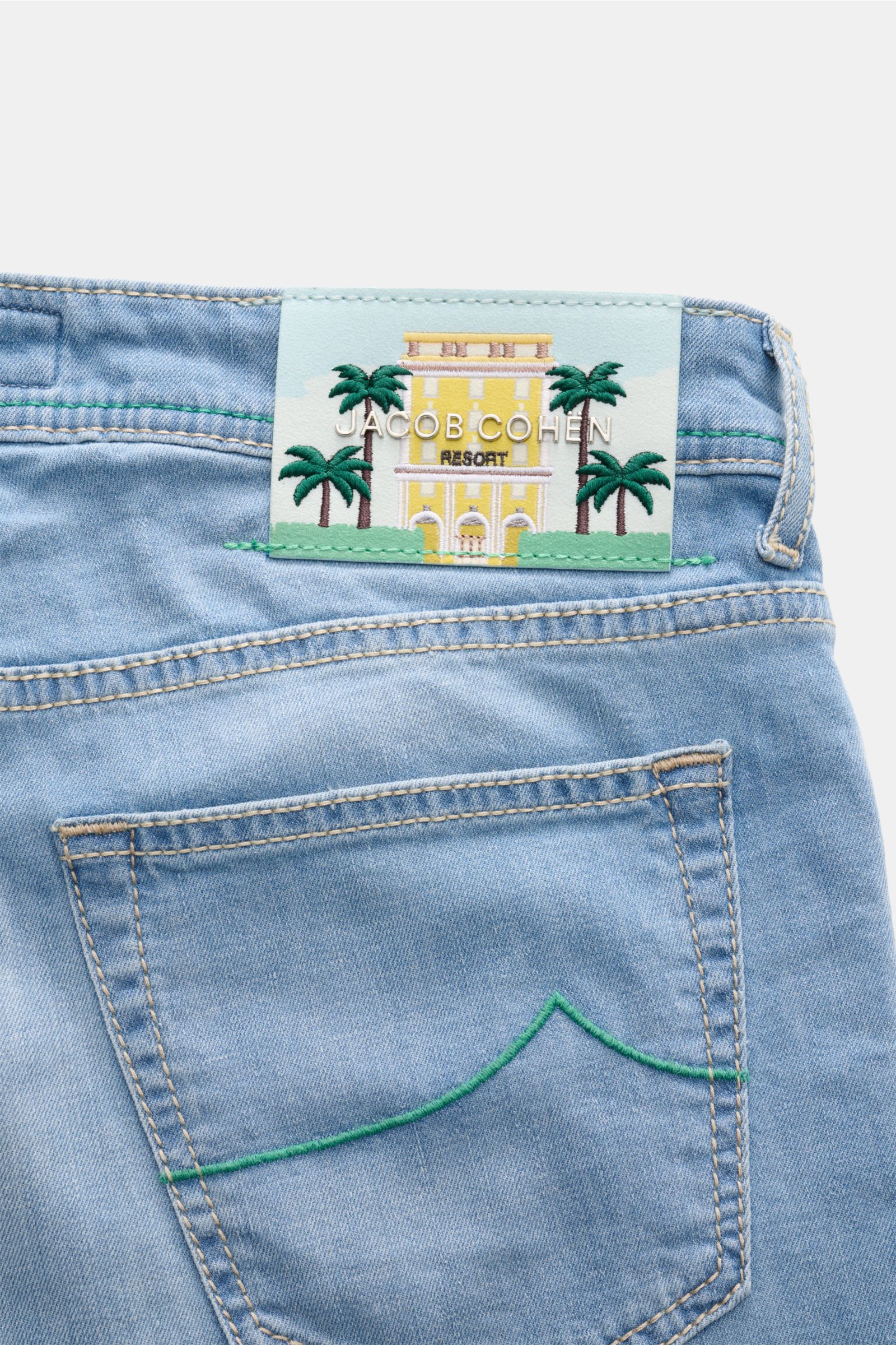 Jacob Cohen Jeans 'Bard LTD' light blue shown from the back upper section, featuring a distinctive calfskin patch with palm tree design, subtle used wash, slim fit, tapered cut, and detailed green stitching on the back pocket. Modern nonchalance combined 
