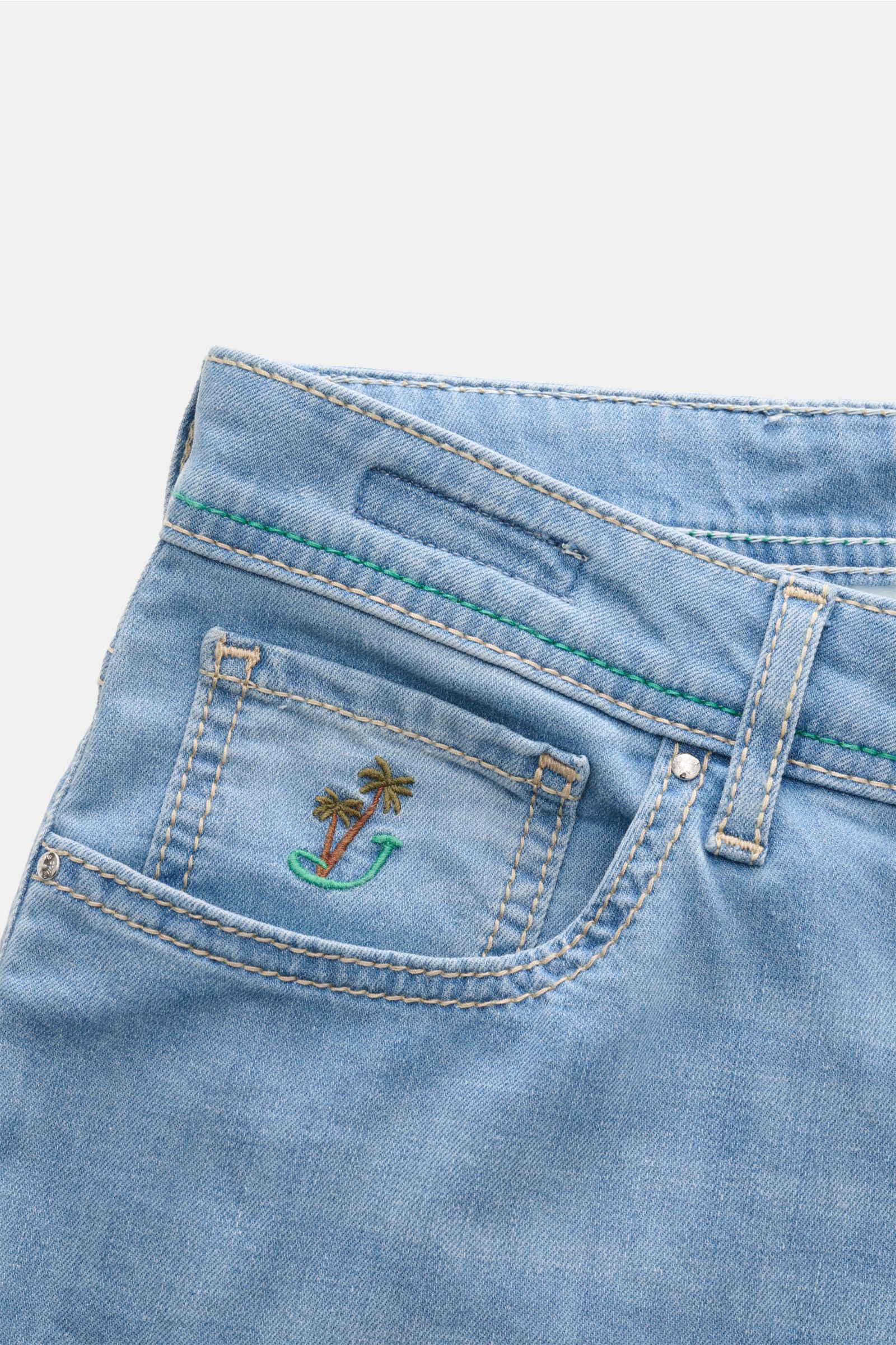 Close-up front view of Jacob Cohen Jeans 'Bard LTD' light blue showing coin pocket with embroidered palm tree logo, belt loop, and stitching. Modern nonchalance combined with unmistakeable details like the distinctive calfskin patch: these, along with the