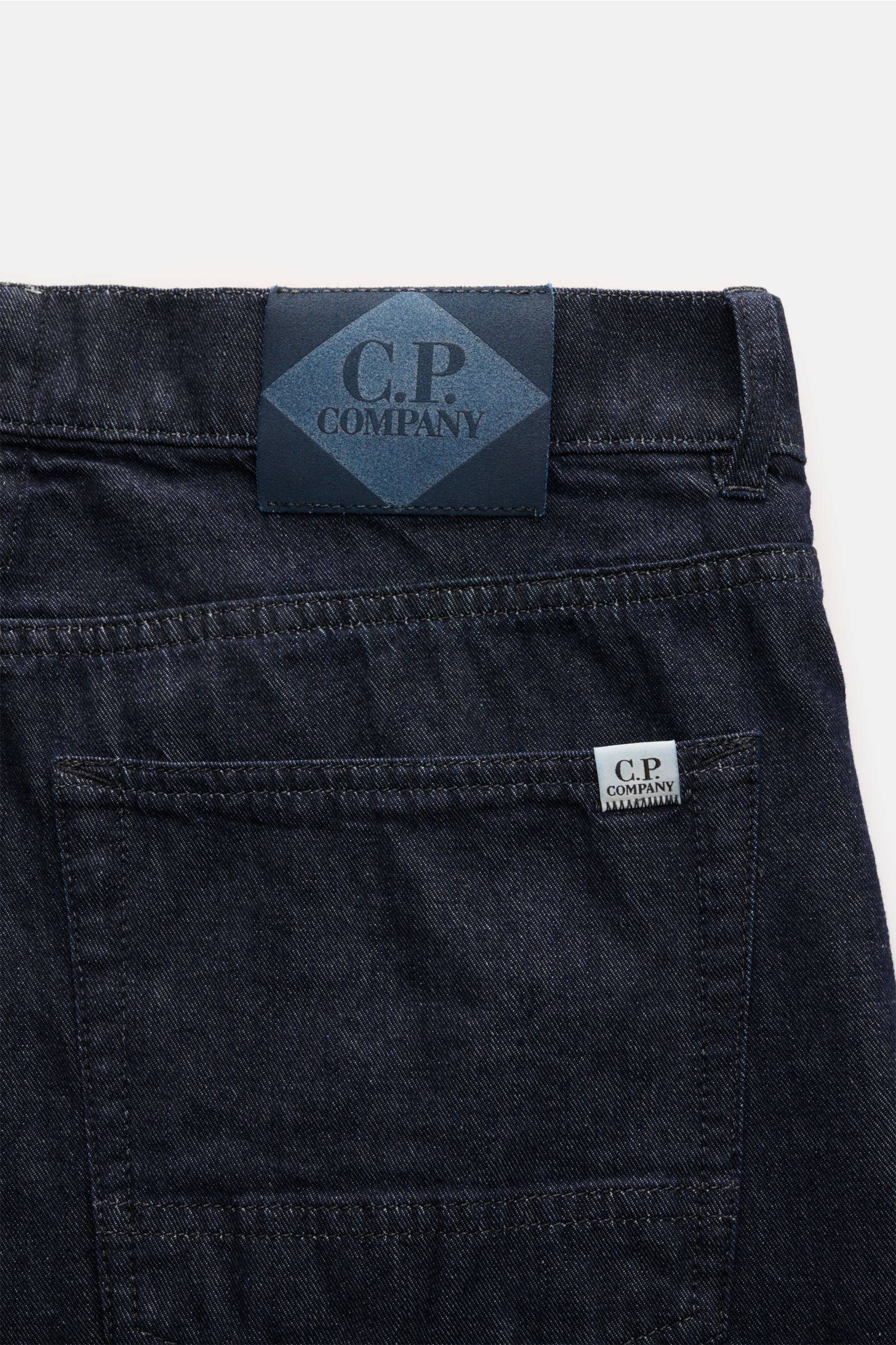 C.P. Company Jeans navy in Tapered Fit aus reiner Baumwolle, knöchellang, Five-Pocket-Stil, Lederpatch, Rückansicht nah fotografiert.