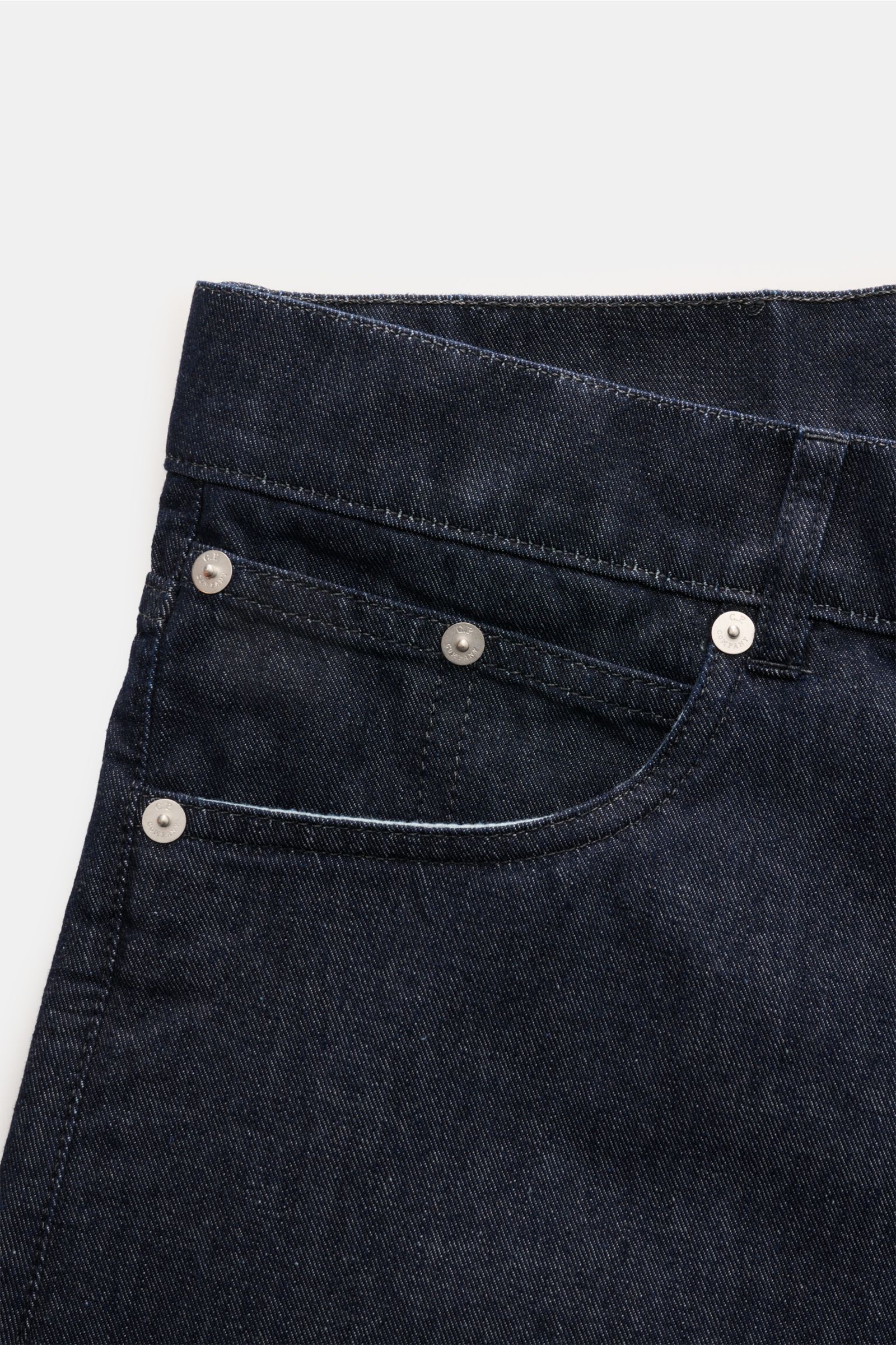 Close-up image of the front top section of C.P. Company Jeans navy from a front angle, showing the five-pocket style with silver rivets and detailed stitching on pure cotton denim with a slightly robust texture. Timeless companion: These jeans in a tapere