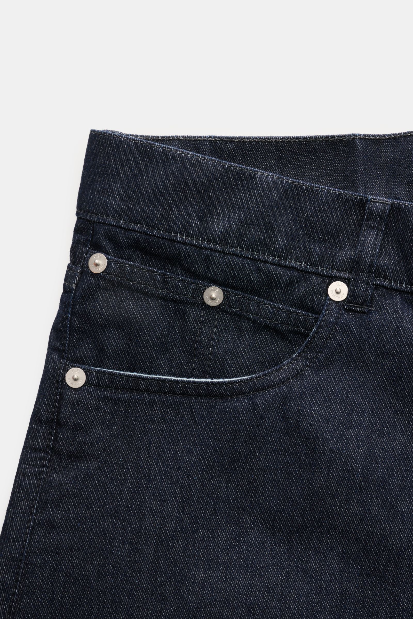 Nahaufnahme der C.P. Company Jeans navy aus reiner Baumwolle mit Five-Pocket-Stil, Button Fly und Leather Patch, frontal fotografiert.