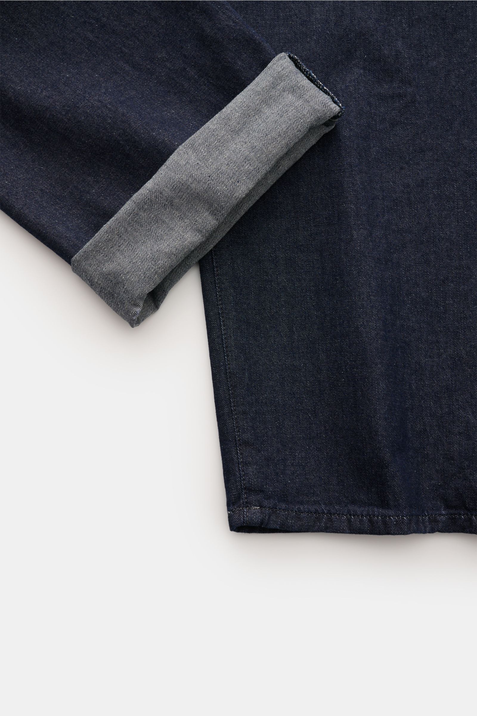 Close-up view of C.P. Company Jeans navy showing the tapered fit and rolled-up ankle, highlighting pure cotton fabric and premium finish.