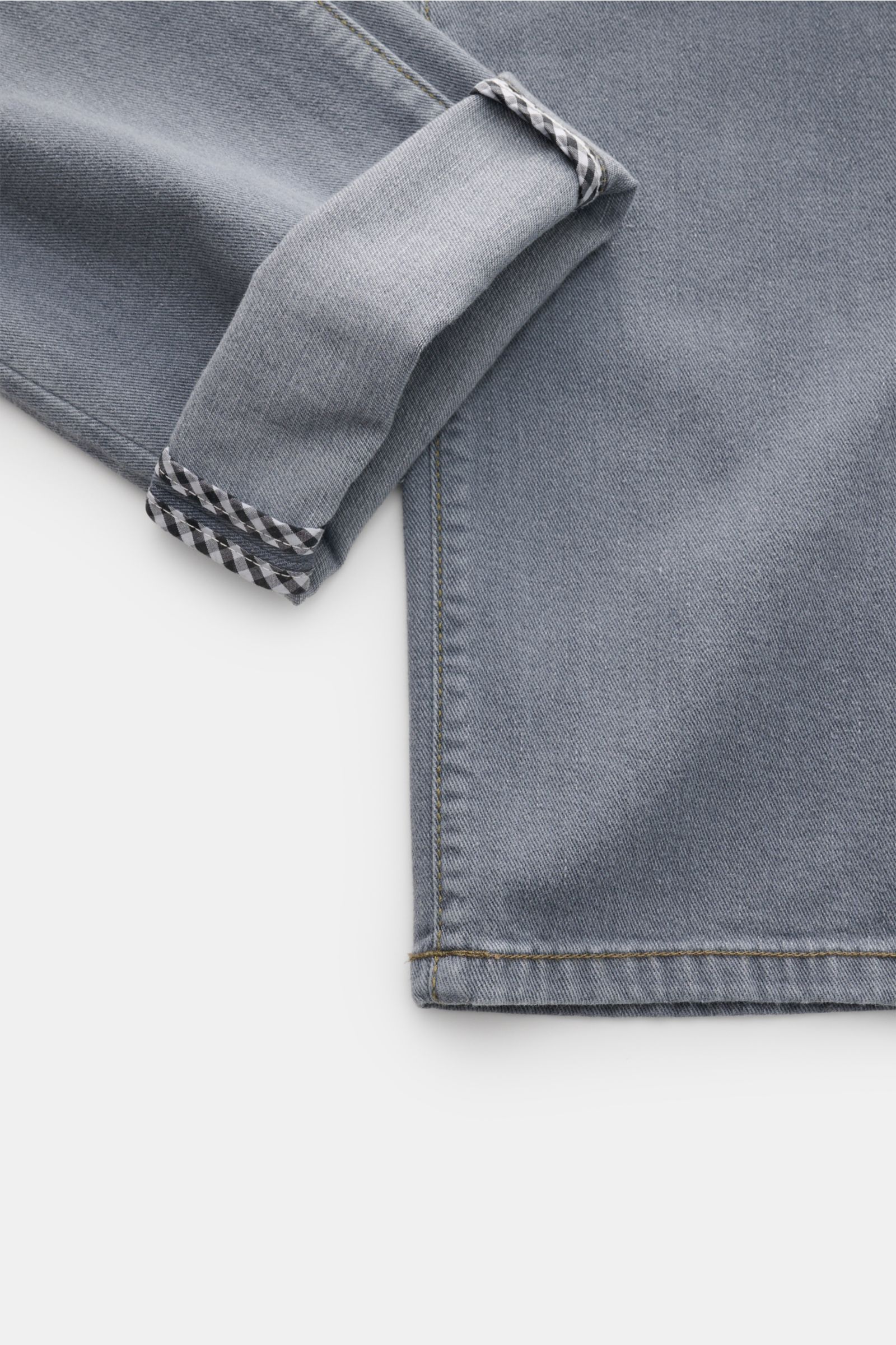 Nahaufnahme der umgeschlagenen Manschette der Richard J. Brown Jeans 'Tokyo' grau aus elastischer Baumwolle, Slim Fit, mit kontrastierendem Innenstoff und sichtbaren Nähten, fotografiert von oben.