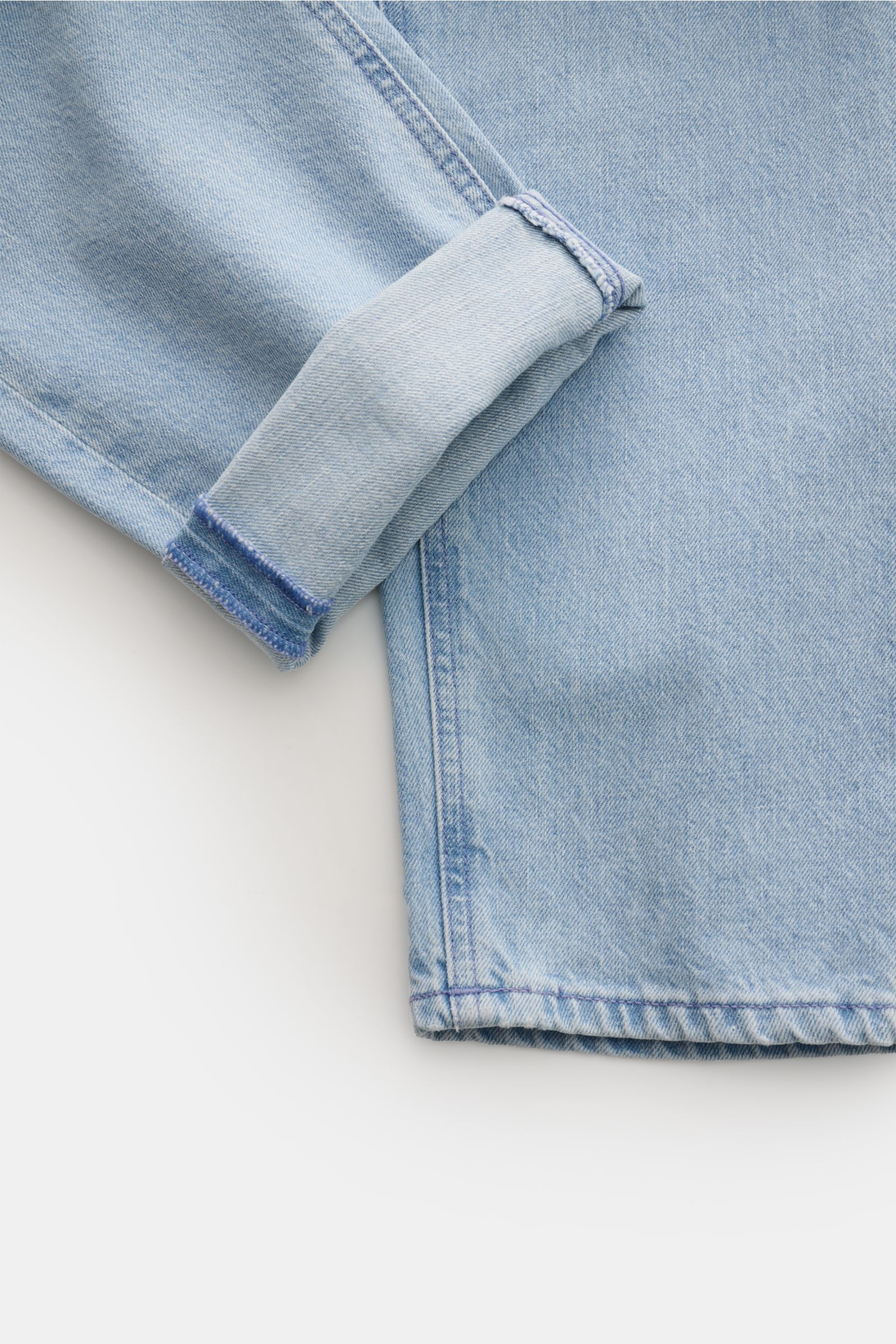 PT Torino Denim Jeans 'Rebel' hellblau im Detail, nah von unten fotografiert, mit gekrempeltem Bein, leichter Used-Waschung, Button Fly und Five-Pocket-Stil.