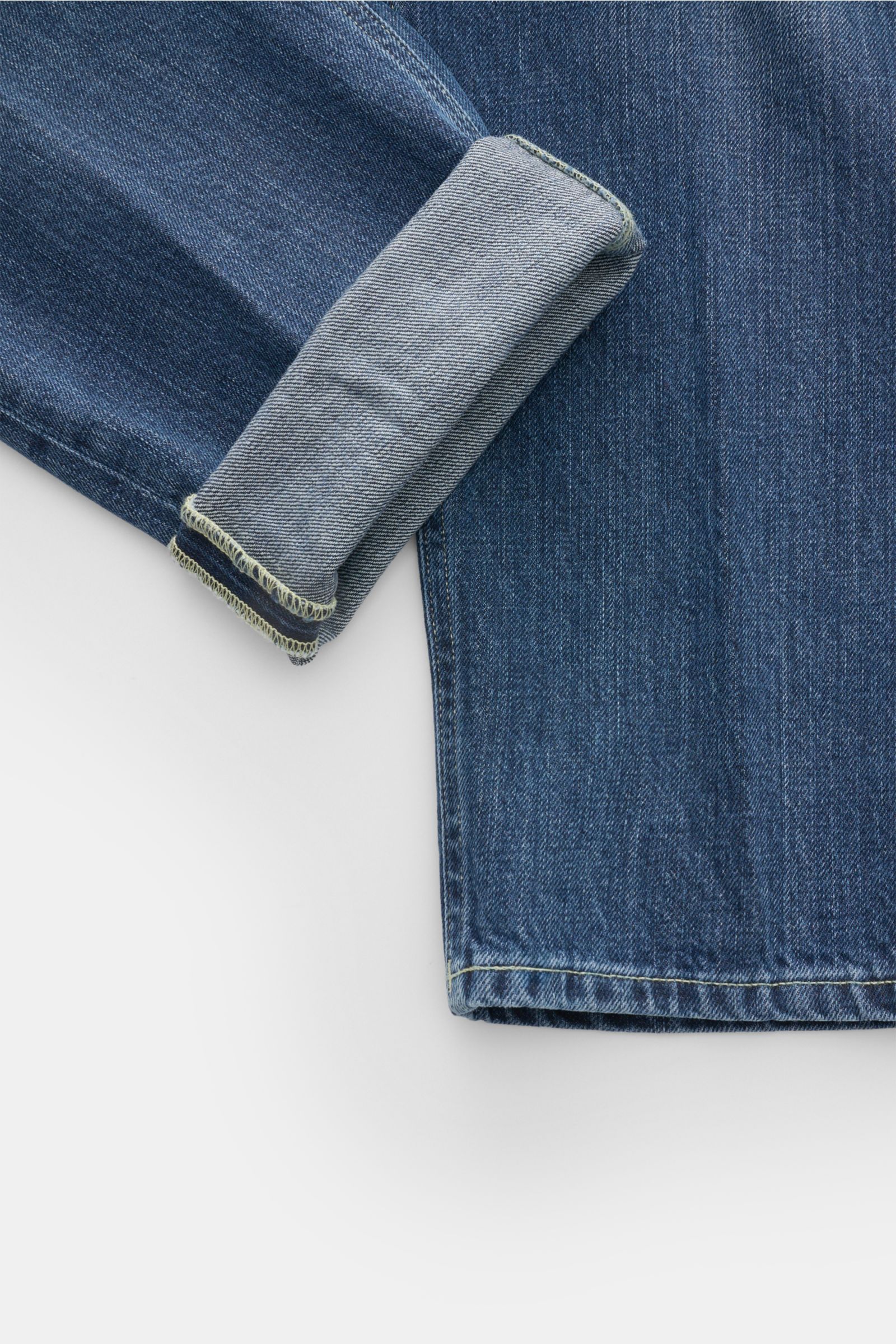 Dondup Jeans 'Paco' dunkelblau, im Detail von schräg oben fotografiert, zeigt den kurzen, schmal zulaufenden Saum mit aufgekrempeltem Bein und authentischer Used-Waschung.