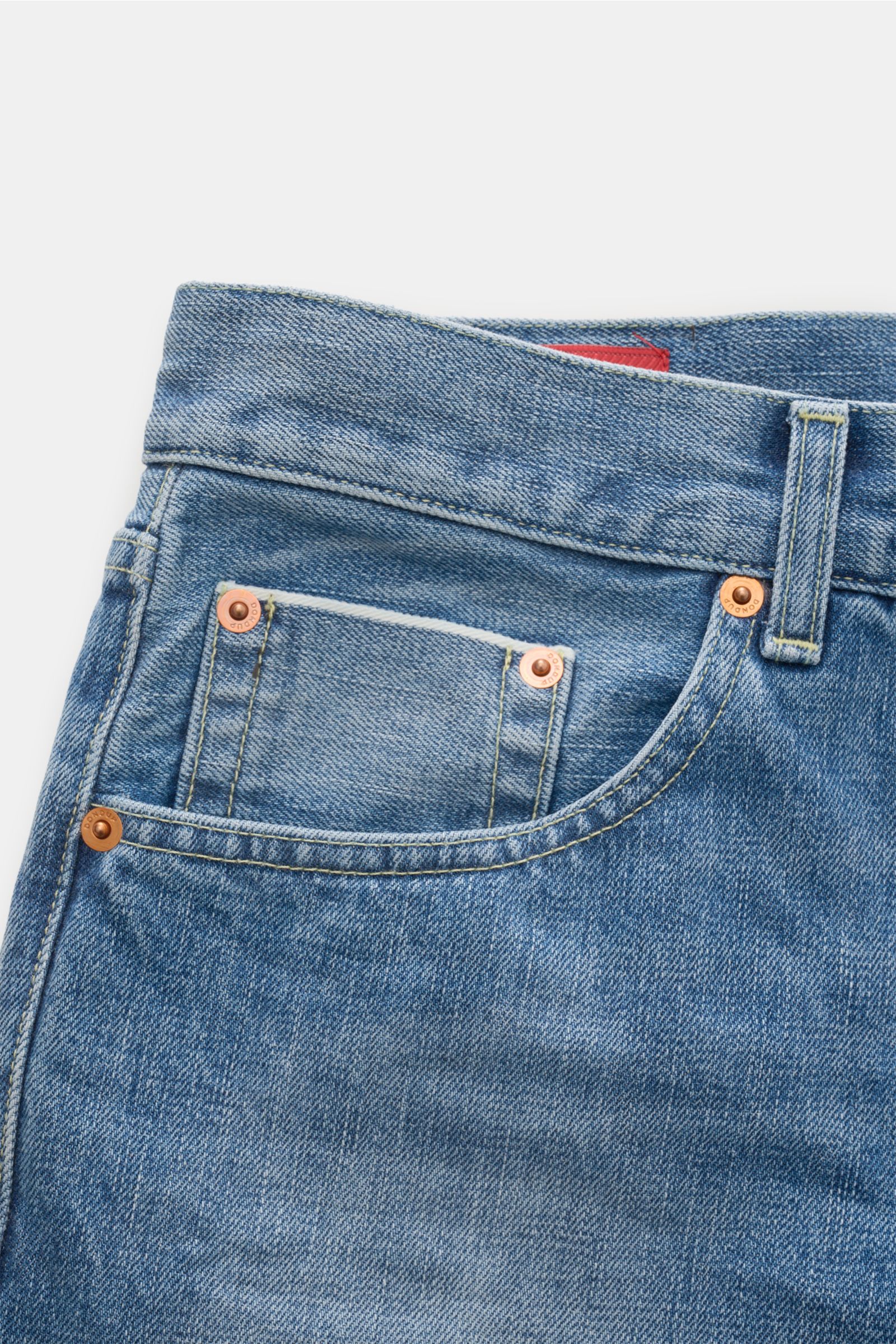 Close-up front-side view of Dondup Jeans 'Bray' rauchblau in soft, pure cotton selvedge denim with authentic used wash, subtle distressed details, regular fit, button fly, five-pocket style, metal rivets, and inner DONDUP label. In Kombination mit weißem 