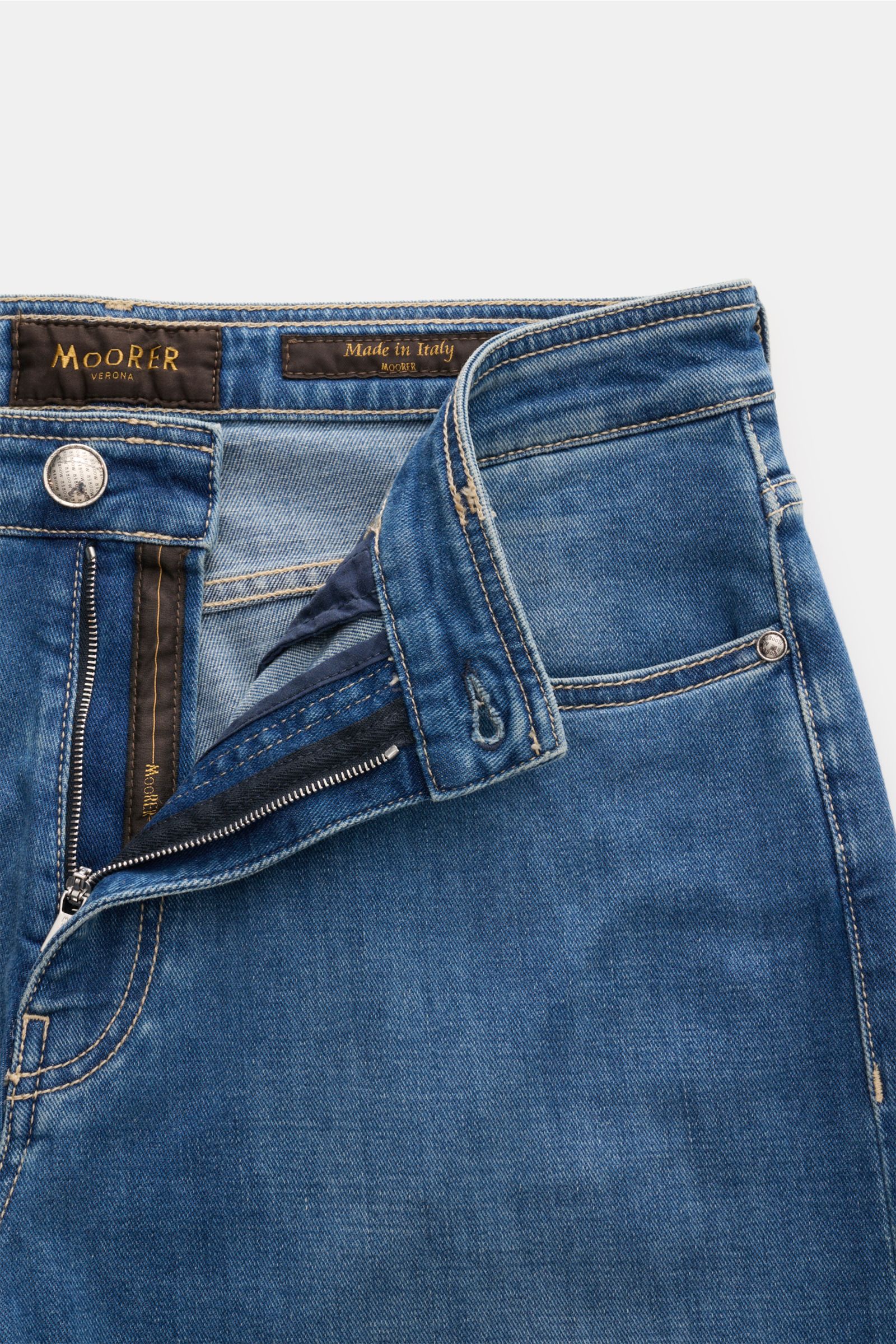 Moorer Jeans 'Milton' rauchblau shown from front close-up with open button fly, elastic cotton denim, soft touch, subtle used wash, regular fit, straight cut, five-pocket style with coin pocket logo and leather patch.