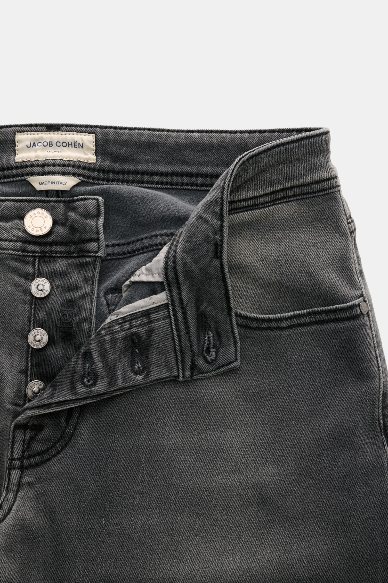 Close-up front view of Jacob Cohen Jeans 'Nick' grey with button fly open, showing elasticated fabric, soft cotton and microfibre denim, subtle used wash, slim fit, tapered cut, five-pocket style with coin pocket featuring initial, back pockets with stitc