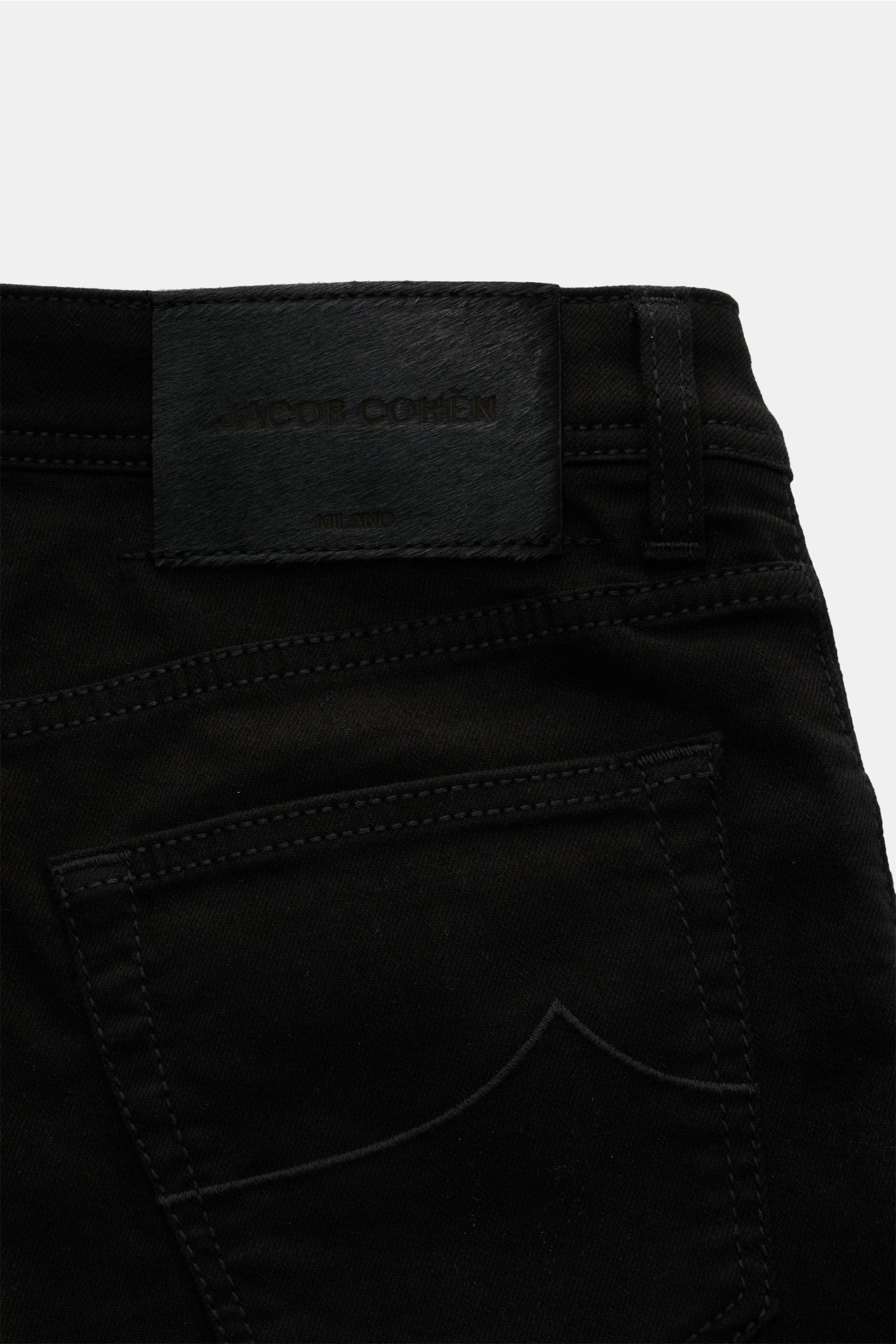 Close-up rear view of Jacob Cohen Jeans 'Nick' black showing back pocket with stitching and leather patch in pony skin look. Denim made of cotton and microfibre, elasticated fabric, soft feel, slim fit, tapered cut, button fly, five-pocket style, coin poc