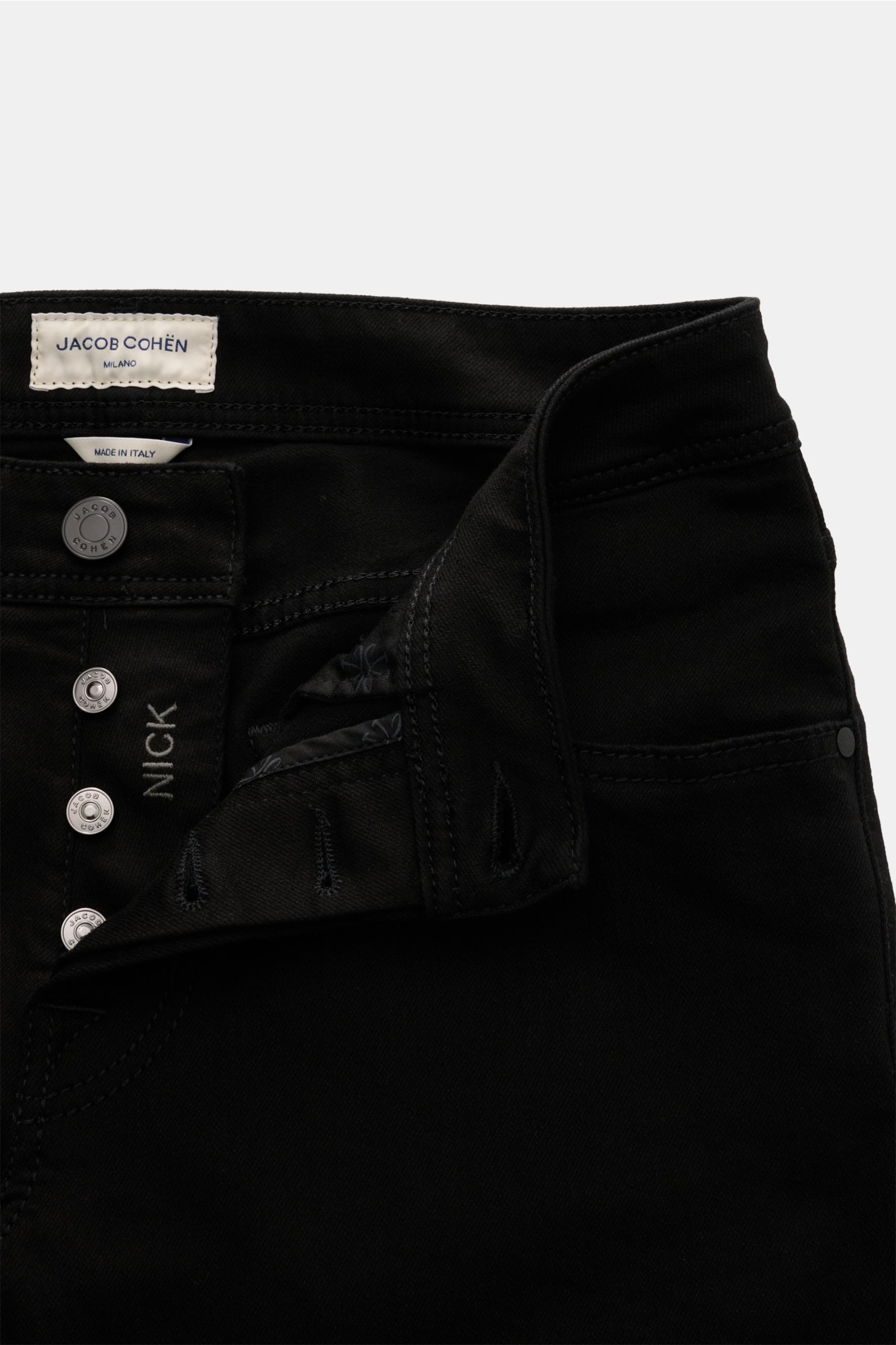 Close-up front view of Jacob Cohen Jeans 'Nick' black showing button fly, elasticated fabric, and five-pocket style. Denim made of cotton and microfibre, soft feel, slim fit, tapered cut, coin pocket with initial, back pockets with stitching, and leather 