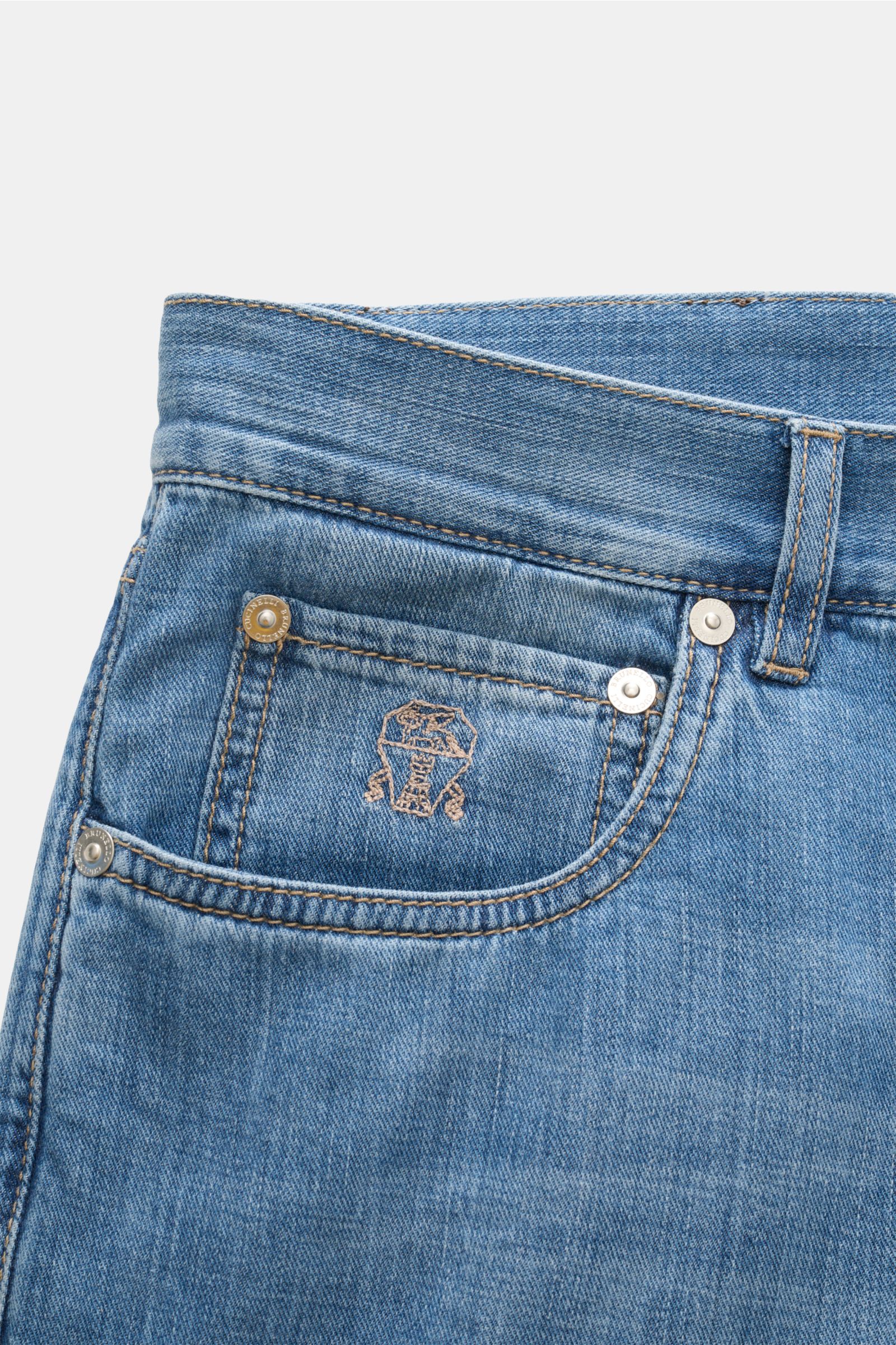 Close-up front view of Brunello Cucinelli Jeans 'Iconic Fit' smoky blue featuring pure cotton denim, soft fabric, authentic used wash, slim fit, very tapered cut, high waist, button fly, five-pocket style, coin pocket with logo stitching, and suede patch.