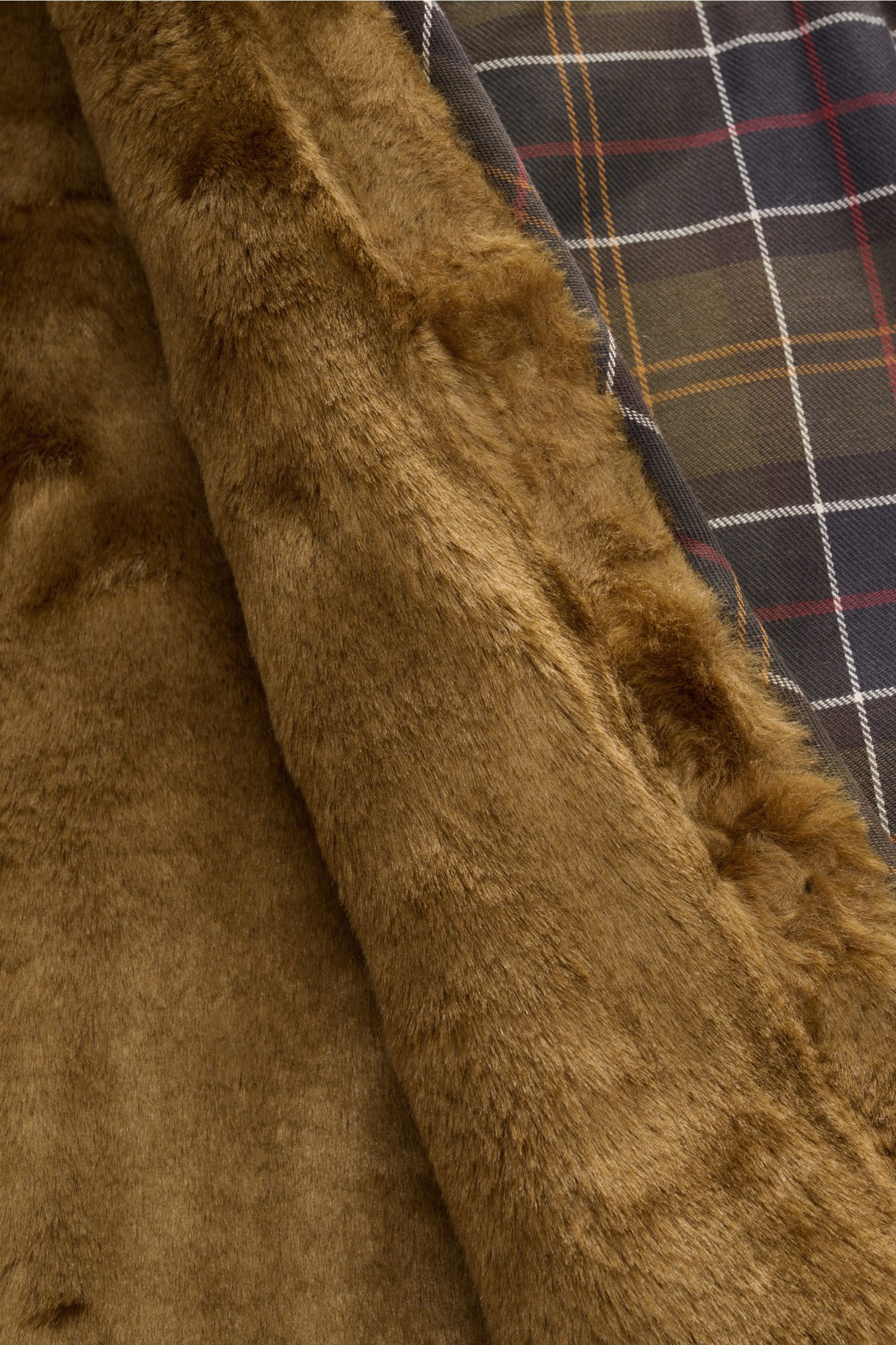 Nahaufnahme der Barbour Weste 'Liner' oliv/braun/rot kariert zeigt das weiche Webpelz-Innenfutter und das traditionelle Tartan-Muster.