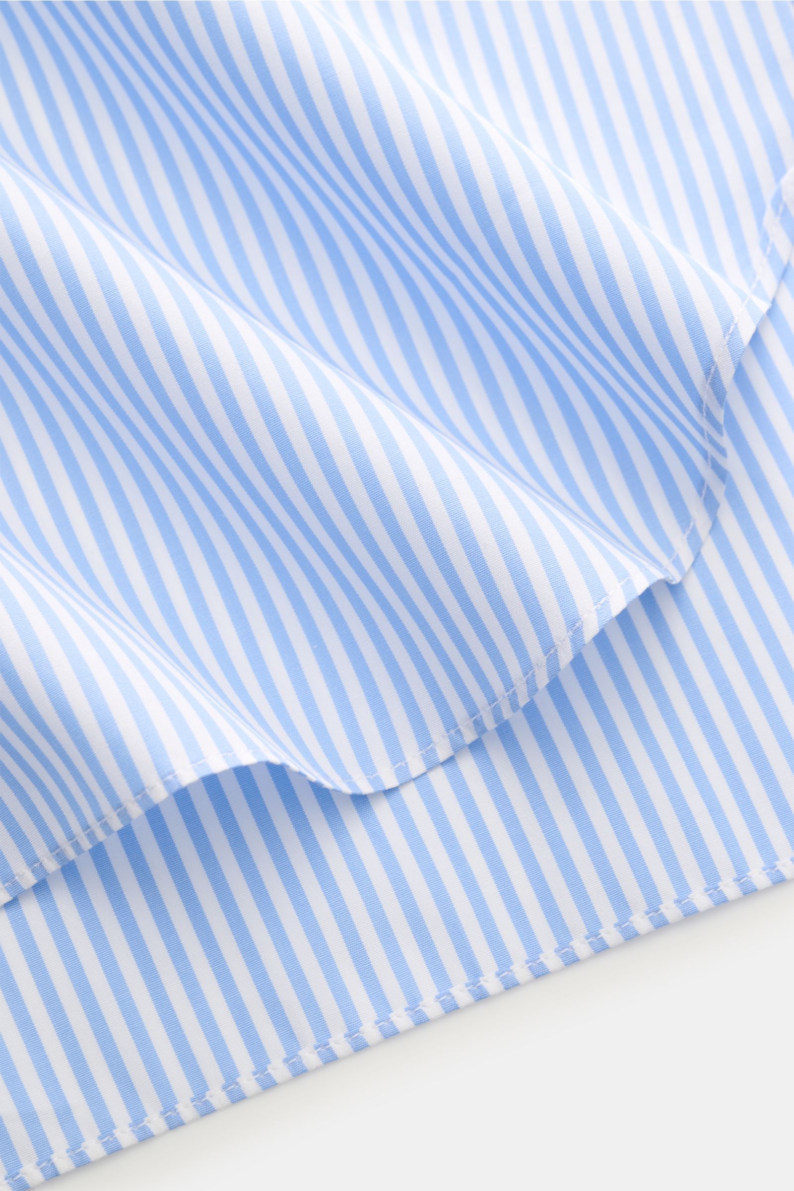 Finamore Business shirt 'Rodi Napoli' Kent collar light blue/white striped fabric detail, close-up from an angled top view, cotton poplin, smooth feel, slim fit, extra-long sleeves, Kent collar, French button placket, classic barrel cuffs, rounded hem.
