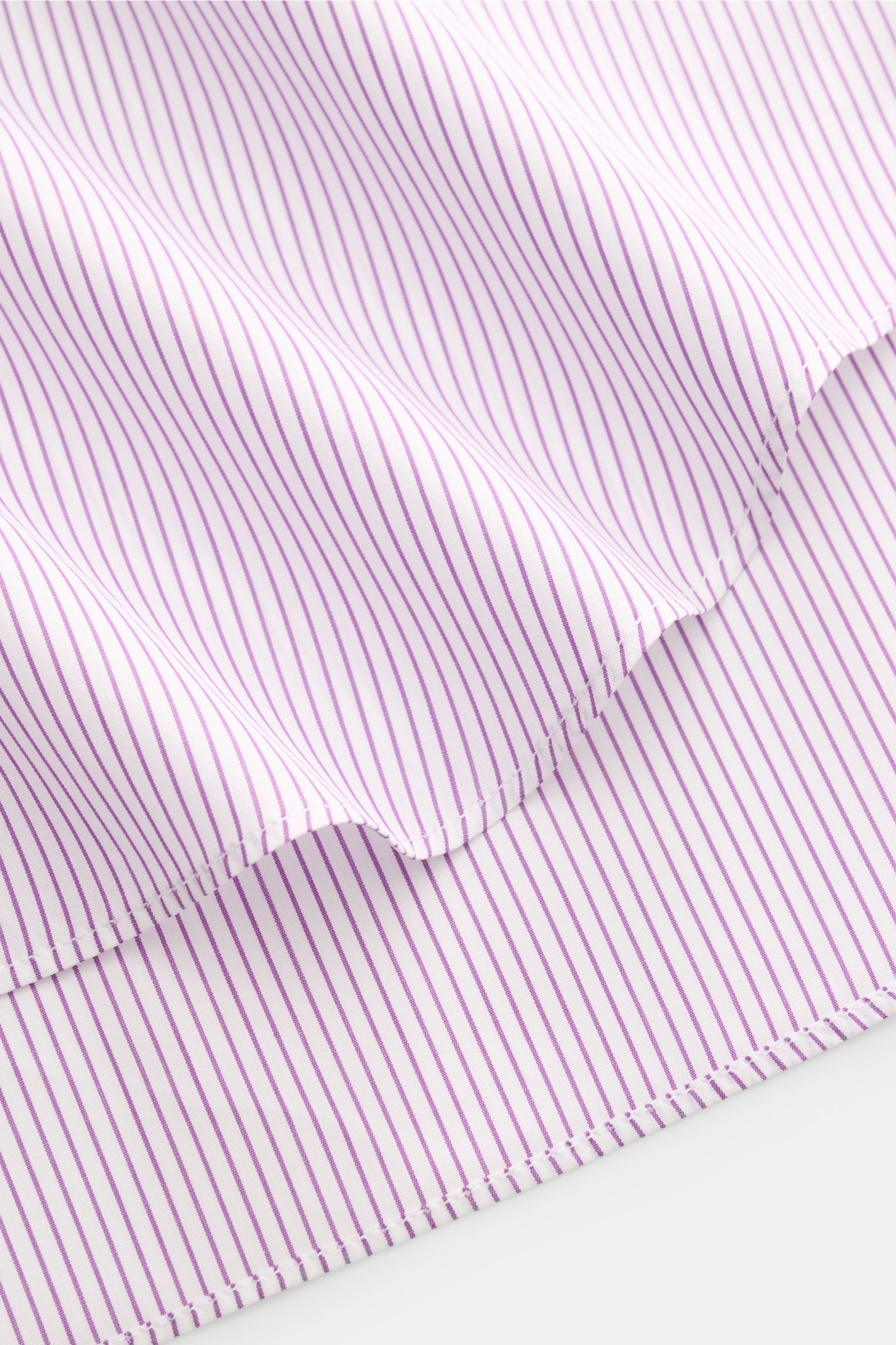 Nahaufnahme des violett/weiß gestreiften Finamore Business Hemd 'Sergio Milano' Haifisch-Kragen aus reiner, kühler Baumwolle mit französischer Knopfleiste, klassischer Sportmanschette und gerundetem Saum, fotografiert von schräg oben.