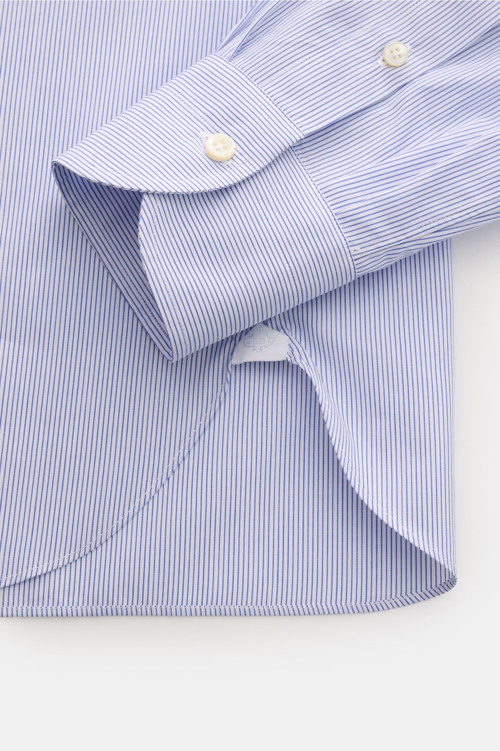 Close-up view of Borrelli Business shirt 'Nando' shark collar dark blue/white striped cuff and rounded hem, showcasing mother-of-pearl buttons.

Description: 
Timeless classic: The shirt 'Nando' from BORRELLI features classic, elegant design and unbeat
