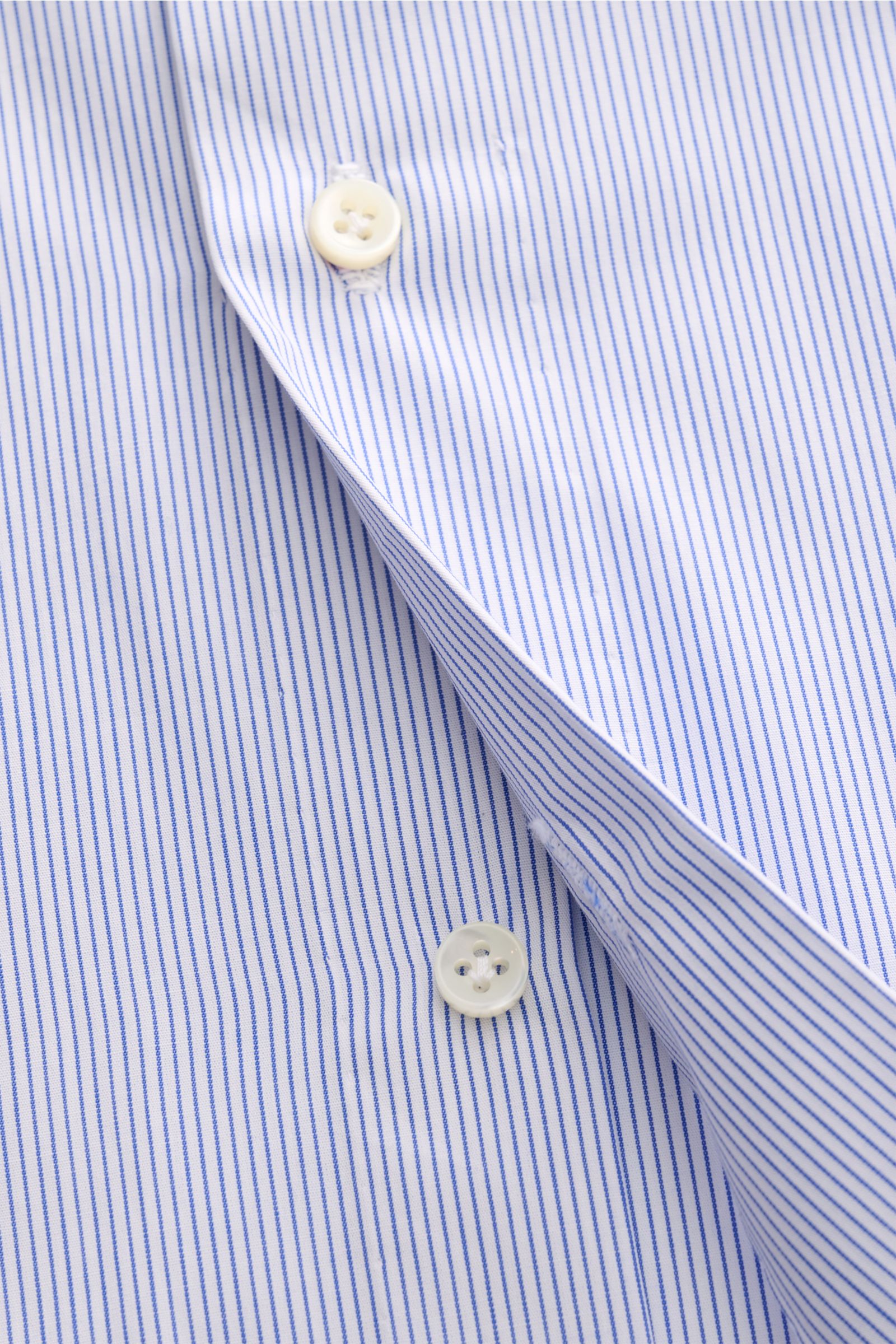 Close-up top-down view of Borrelli Business shirt 'Nando' shark collar dark blue/white striped showing fine blue stripes, mother-of-pearl buttons, and smooth cotton popeline fabric.

Timeless classic: The shirt 'Nando' from BORRELLI features classic, e