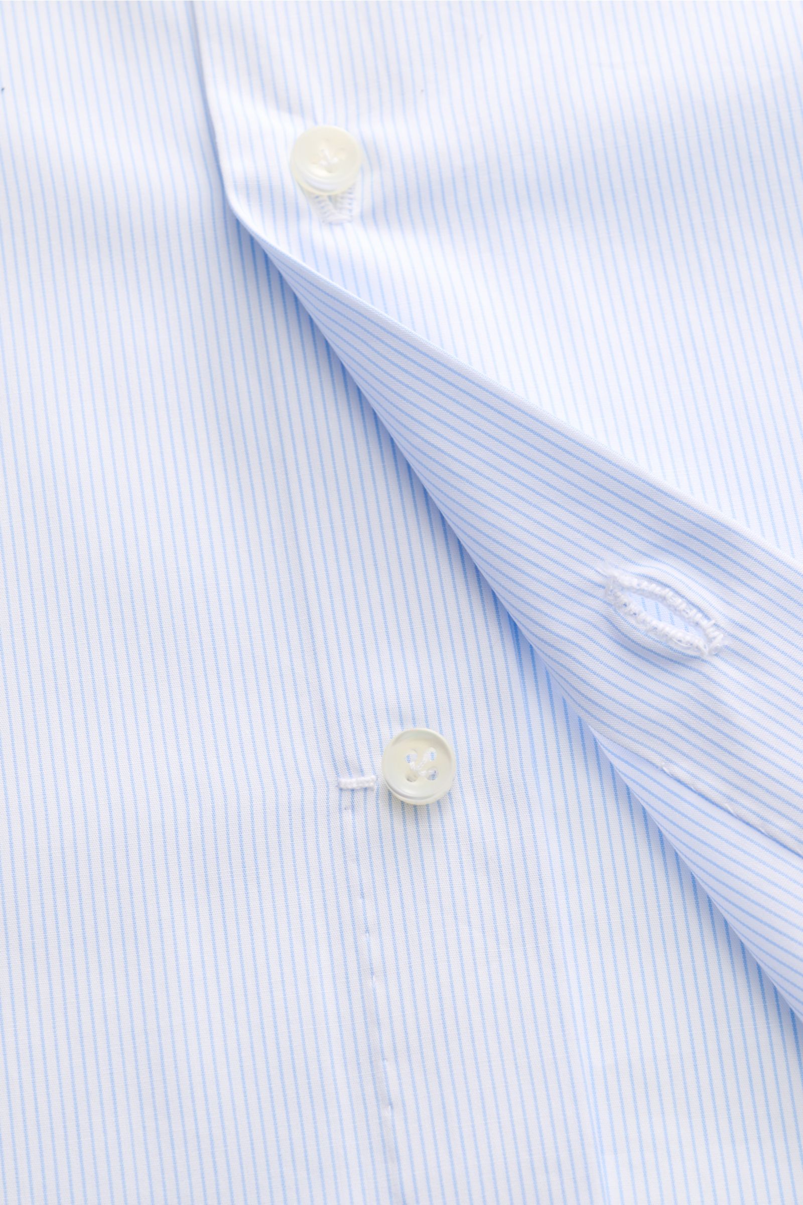 Borrelli Business Hemd 'Nando' Haifisch-Kragen hellblau/weiß gestreift shown close-up from above, highlighting fine stripes, buttons, and fabric texture.  
Zeitloser Klassiker: Das Hemd 'Nando' von BORRELLI überzeugt mit klassischem Design und unvergle