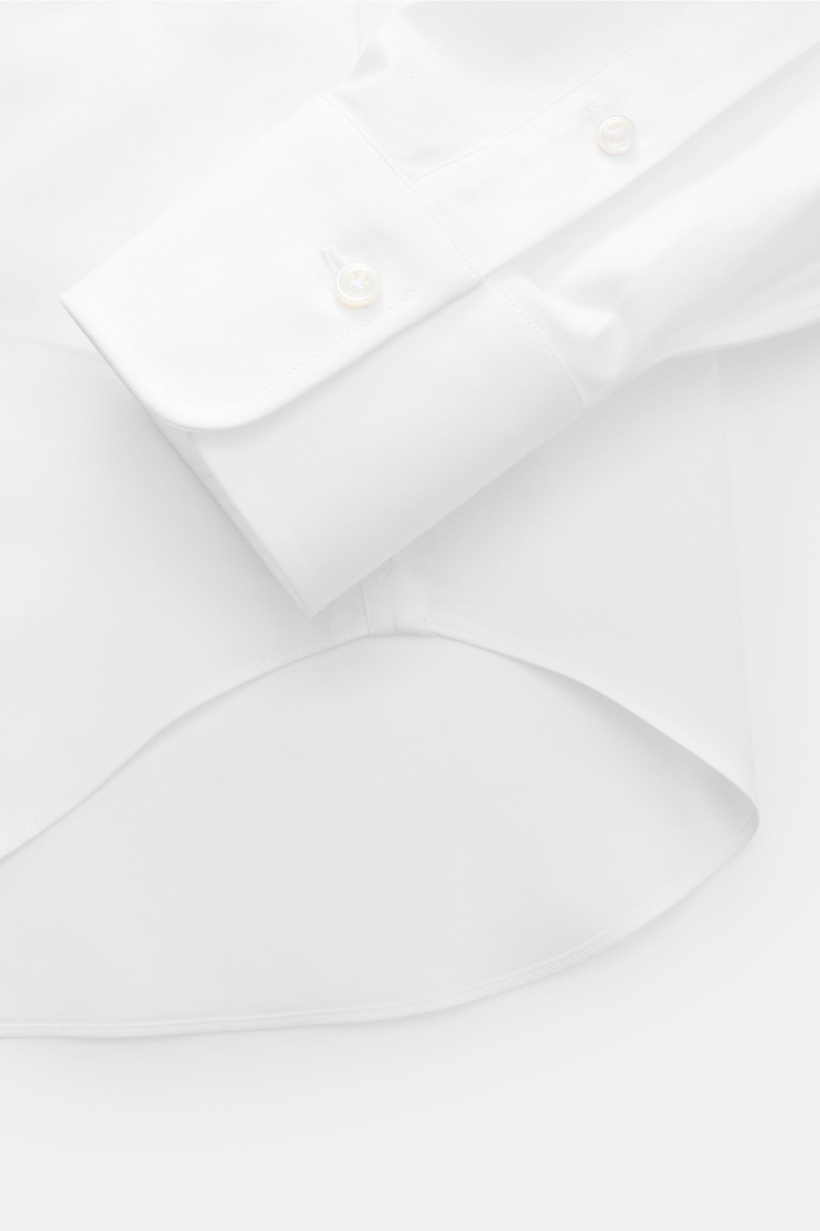 Close-up image of the Gherardi Business shirt shark collar white showing the sleeve cuff and rounded hem from a top-down perspective, made of pure cotton gabardine with smooth touch, lightweight fabric, slim fit, shark collar, French button placket, class