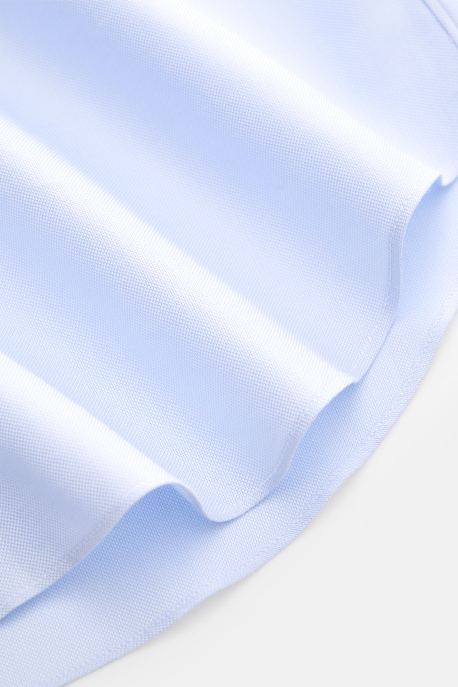 Close-up of light blue Gherardi Business Hemd Haifisch-Kragen hellblau fabric showing Panama cotton texture and hem edge from a side angle. Elegantes Business Hemd mit Sportmanschette von GHERARDI: feinste Baumwolle in Premium-Qualität, kombiniert mit ein