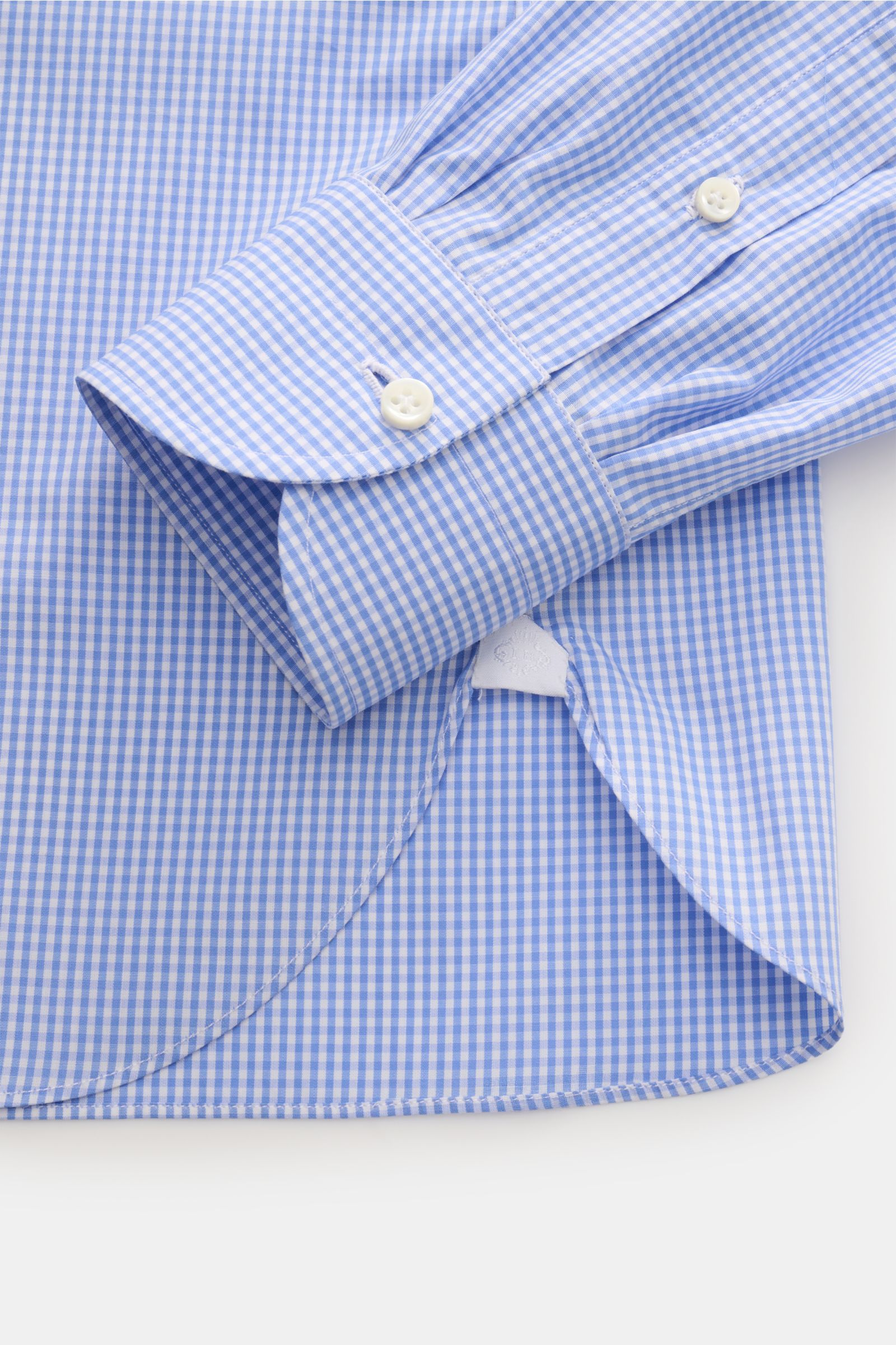 Close-up image of the cuff and hem of the Borrelli Business shirt 'Nando' shark collar blue/white checked, photographed from above, showing pure cotton popeline, light smooth touch, classic striped pattern, slim fit, shark collar, French button placket wi