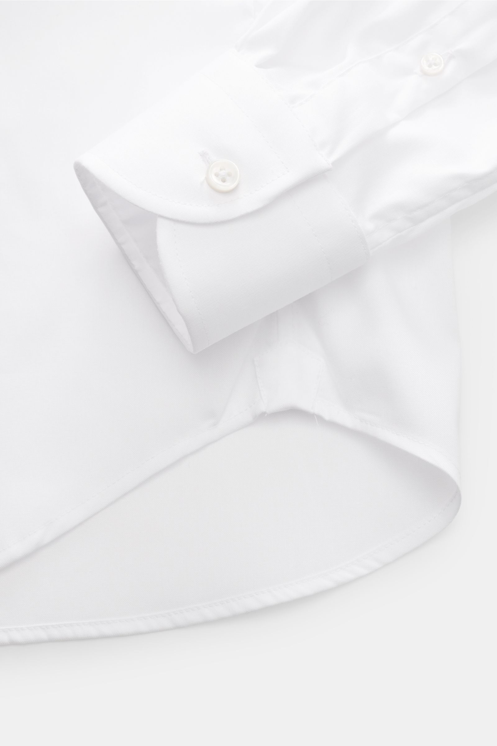 Nahaufnahme des gerundeten Saumverlaufs und der klassischen Sportmanschette mit Knopf des BRAUN Hamburg Business Hemd Haifisch-Kragen weiß aus feinem Baumwoll-Pinpoint, glattem Griff, Extra Slim Fit, Haifisch-Kragen und französischer Knopfleiste.
