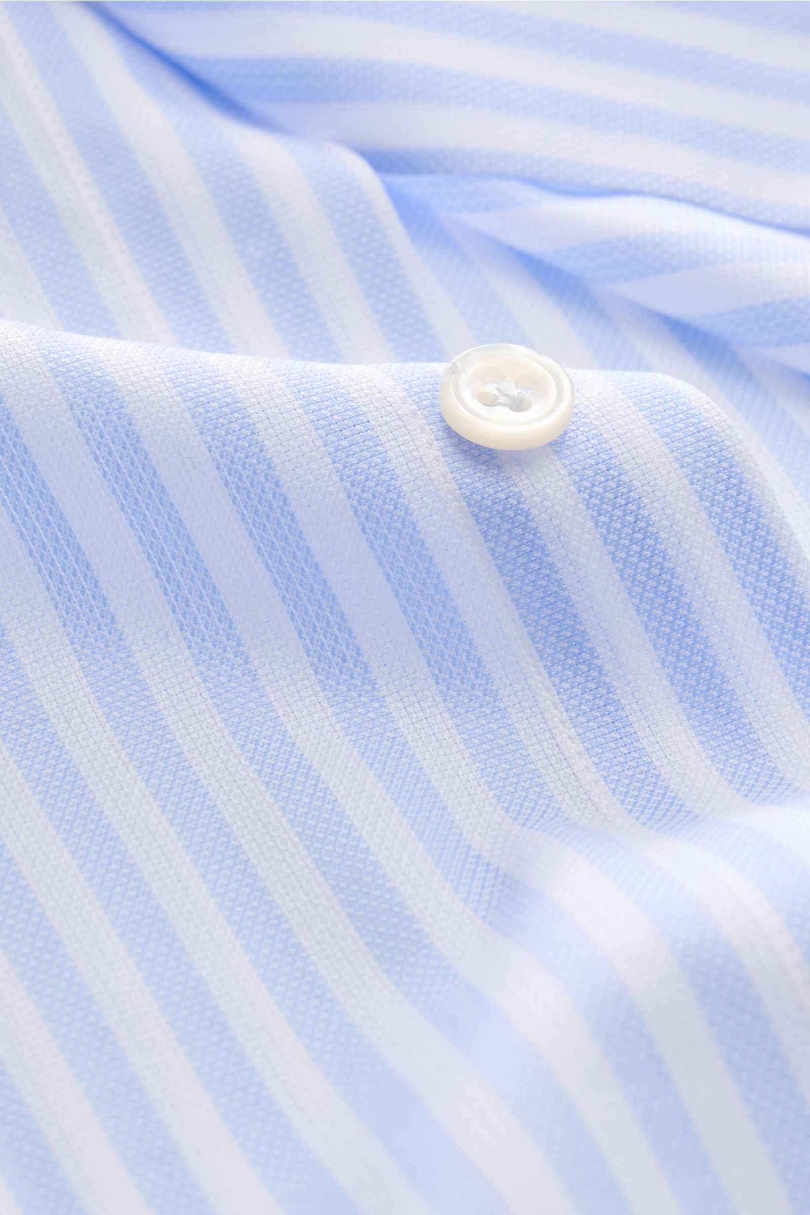 Close-up front view of Finamore Business shirt 'Sergio Napoli' shark collar light blue/white striped showing fabric texture and button. A classic by FINAMORE: This business shirt in a striped design features excellent workmanship and timeless elegance.