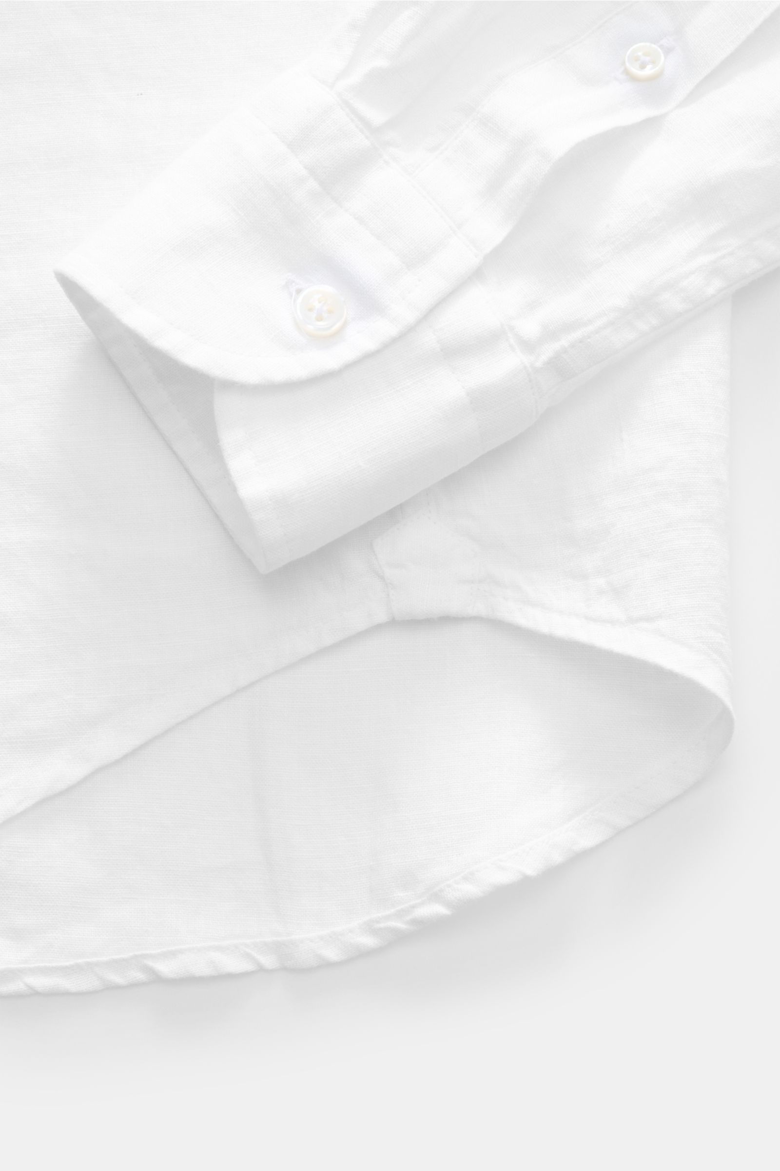 Nahaufnahme von der Ärmelmanschette und dem gerundeten Saum des von Braun Leinenhemd Haifisch-Kragen weiß, aus reinem Leinen, luftig und leicht.