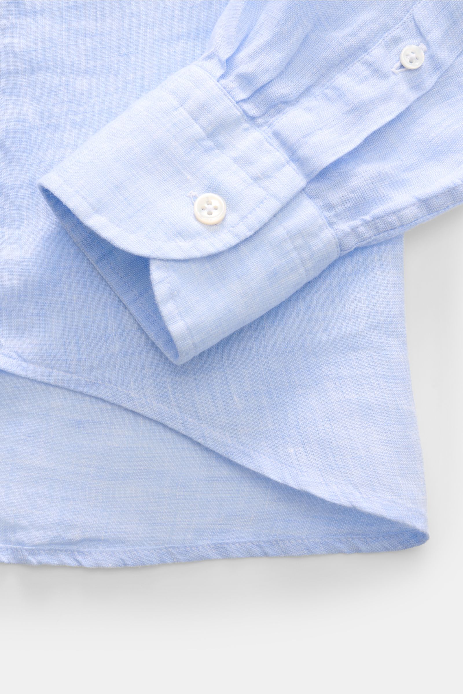 Close-up view of the sleeve and cuff of the von Braun Leinenhemd Haifisch-Kragen hellblau meliert, showcasing the light blue melange linen fabric, classic sport cuff with white button, and fine material texture. Mühelose 