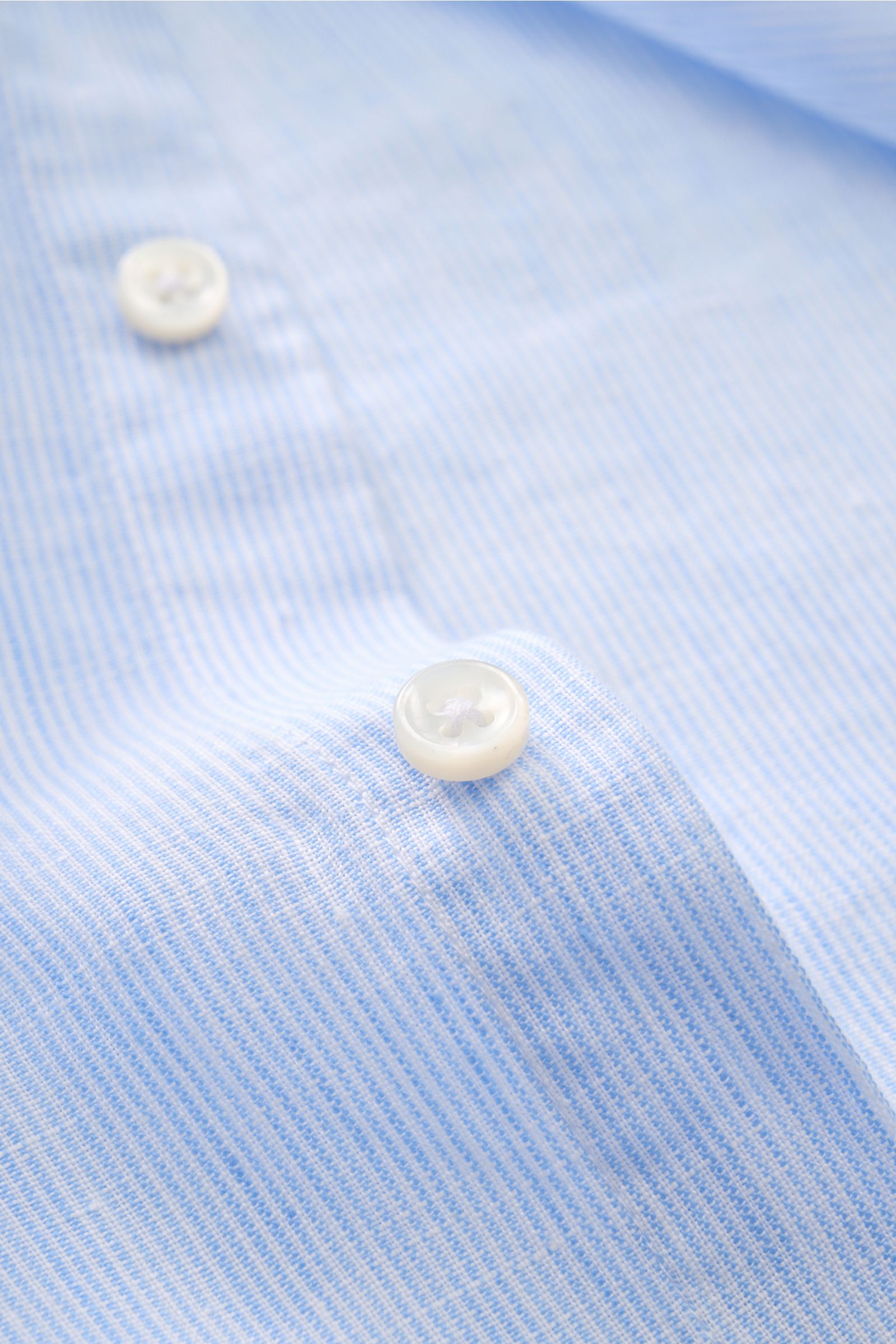von Braun Leinenhemd Haifisch-Kragen hellblau/weiß gestreift close-up from above showing white buttons on fine striped linen fabric, Mühelose Leichtigkeit: Dieses VON BRAUN Hemd aus reinem Leinen überzeugt mit luftigem Tragegefühl und entspanntem Look – e