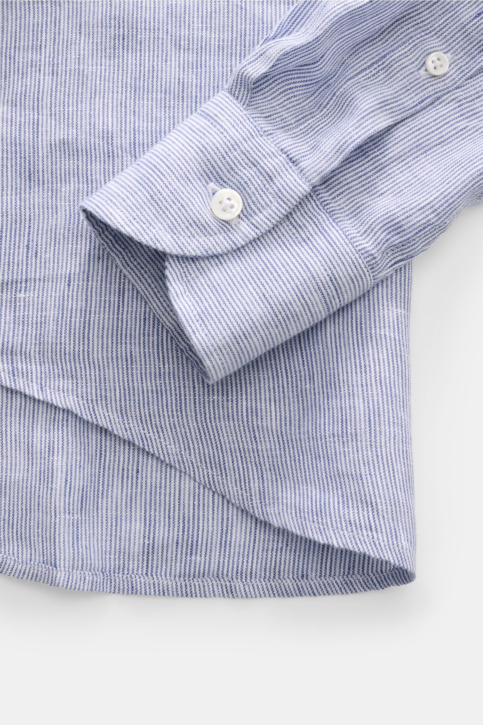 Close-up top view of von Braun Leinenhemd Haifisch-Kragen navy/weiß gestreift cuff and hem, showing fine striped linen fabric, soft texture, and button details. Mühelose Leichtigkeit: Dieses VON BRAUN Hemd aus reinem Leinen überzeugt mit luftigem Tragegef